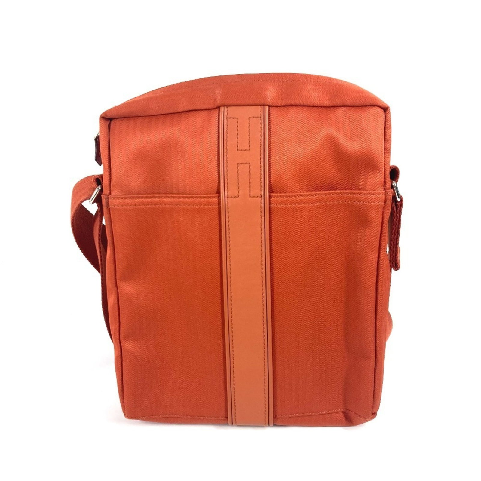 Hermes Pochette Shoulder Bag Nylon Canvas: Hermes Pochette Shoulder Bag Nylon Canvas The Hermes Pochette Shoulder Bag Nylon Canvas is a vibrant orange shoulder bag made from nylon canvas, measuring 26.5cm x 2cm x 5.5cm. This stylish bag comes