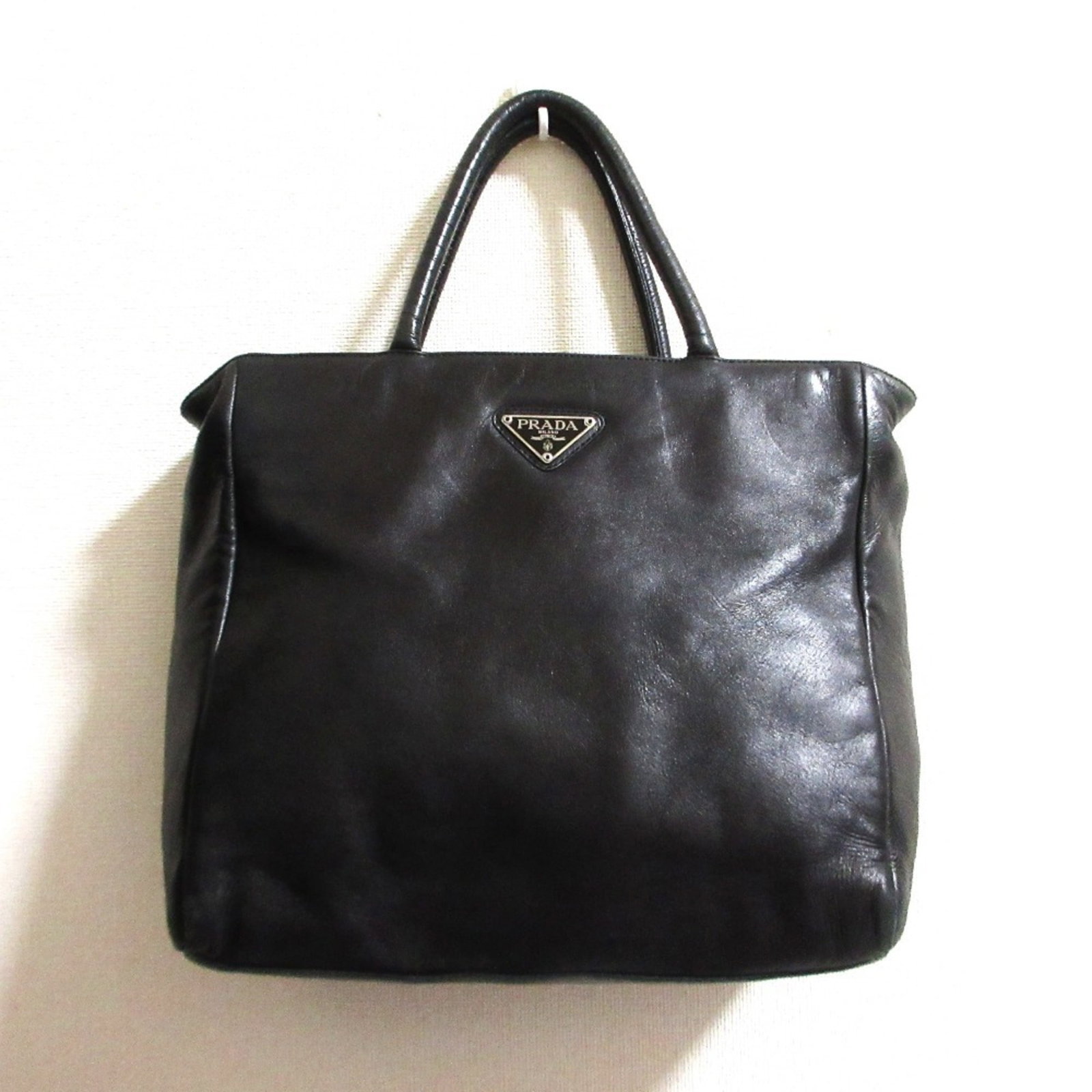 Nappa Leather Prada Tote Bag: Nappa Leather Prada Tote Bag Nappa leather Prada tote bag in black, measuring 26cm x 28cm x 9.5cm, features a 34cm long handle. The bag's material and size provide a compact and stylish option for eve