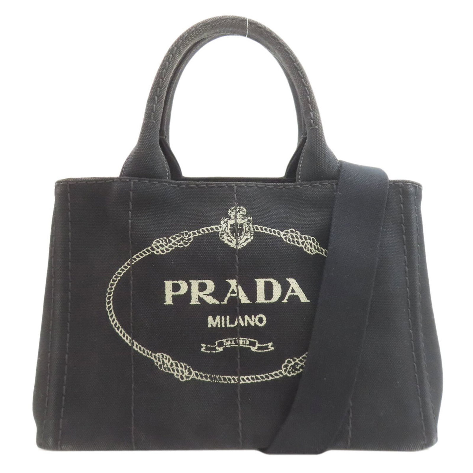 Handbag Canvas by Prada: Handbag Canvas by Prada Canvas by Prada is a black handbag made from canvas material, measuring 19cm x 28cm x 16cm. The bag bears a signature, and its canvas material provides a unique texture. This
