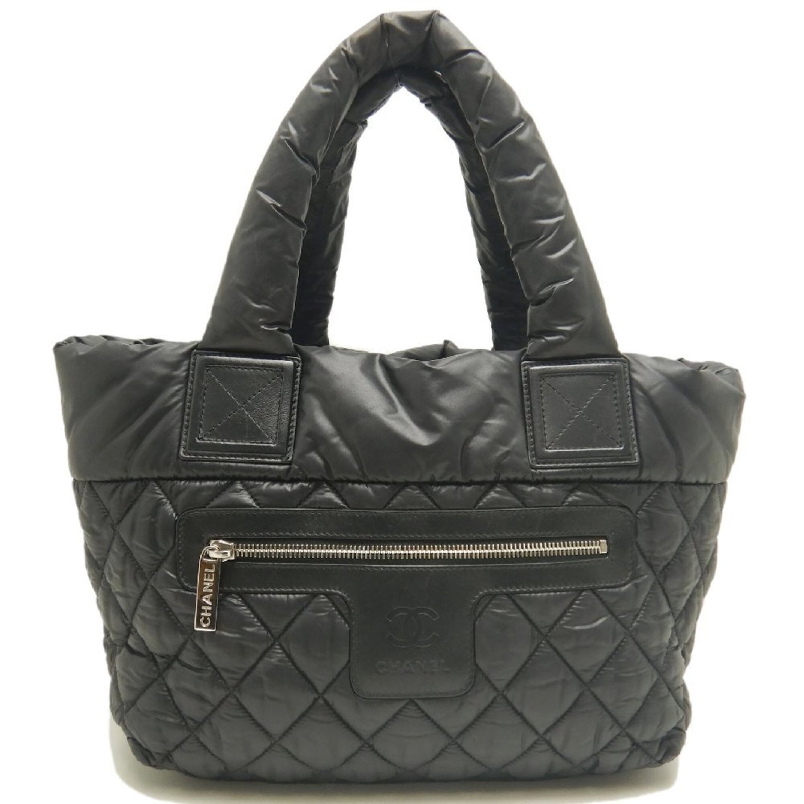 Nylon Tote Bag By Chanel: Nylon Tote Bag By Chanel Nylon Tote Bag by Chanel features a sleek black design with silver hardware, making it a stylish and versatile accessory for everyday use. The bag's compact size and durable