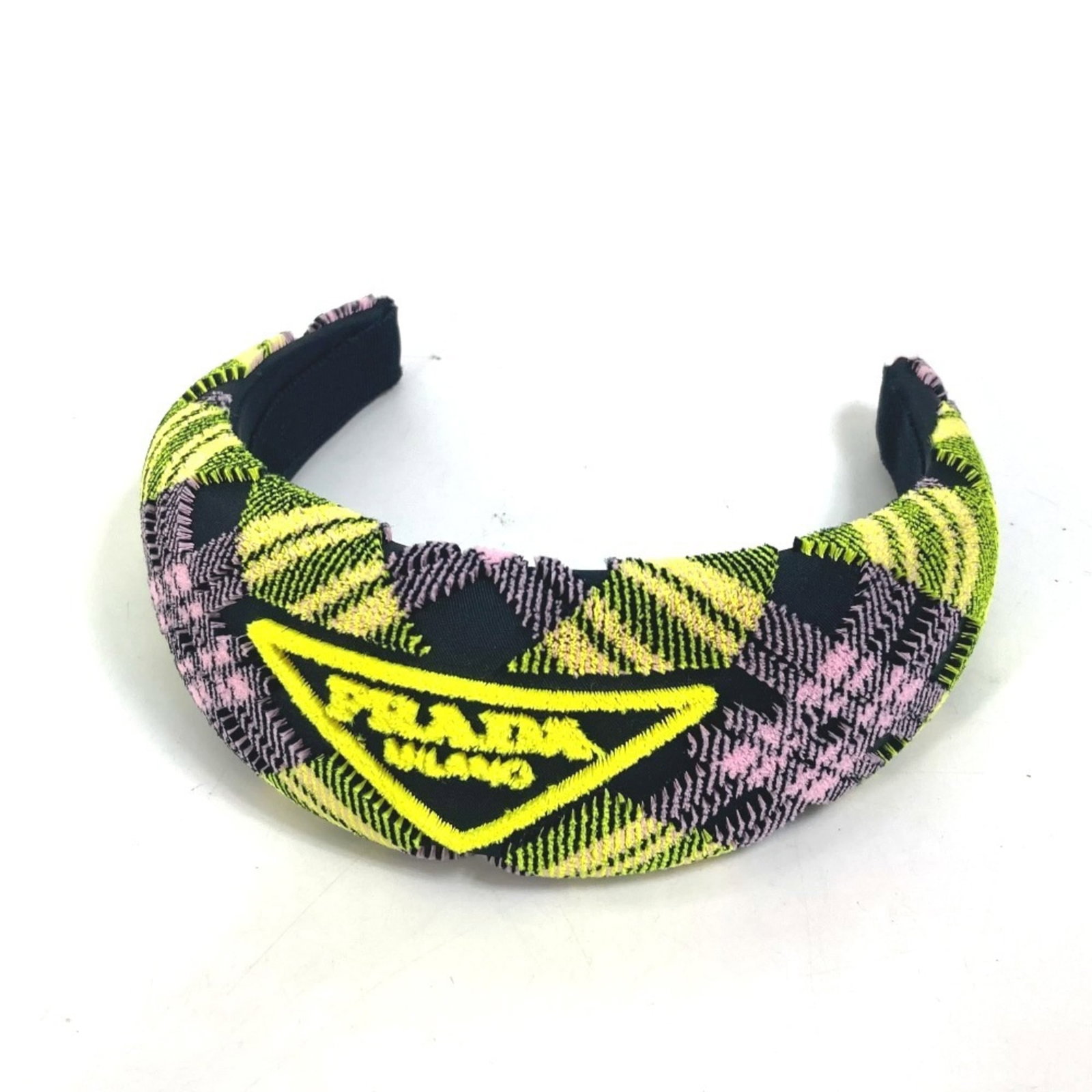 Band Nylon Prada Alice: Band Nylon Prada Alice Triangle logo plate hair accessory in pink and yellow nylon, featuring a 6cm x 2.36'' design. Comes with original box and dust bag. A yellow Prada pile triangle logo plate hair