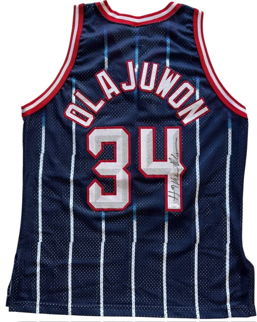 Hakeem Olajuwon Autographed Rockets Authentic Champion Jersey (JSA): Hakeem Olajuwon Autographed Rockets Authentic Champion Jersey (JSA) Signed in black sharpie across the jersey number on the back of the jersey, this Hakeem Olajuwon Autographed Rockets Authentic