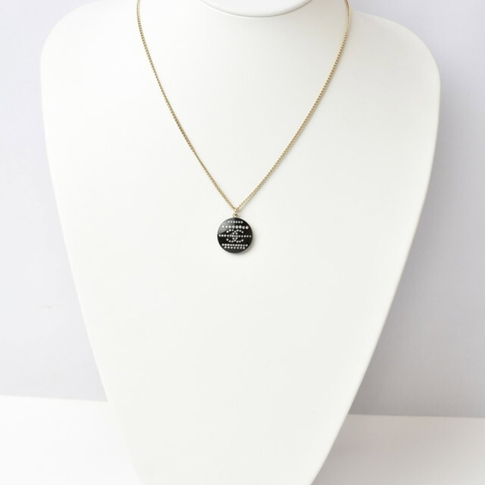 CHANEL Plastic Black Gold: CHANEL Plastic Black Gold Black Gold Rhinestone Pendant Necklace by Chanel, a statement piece featuring a 20mm x 20mm plastic pendant with a subtle gold finish, set against a sleek black background. T