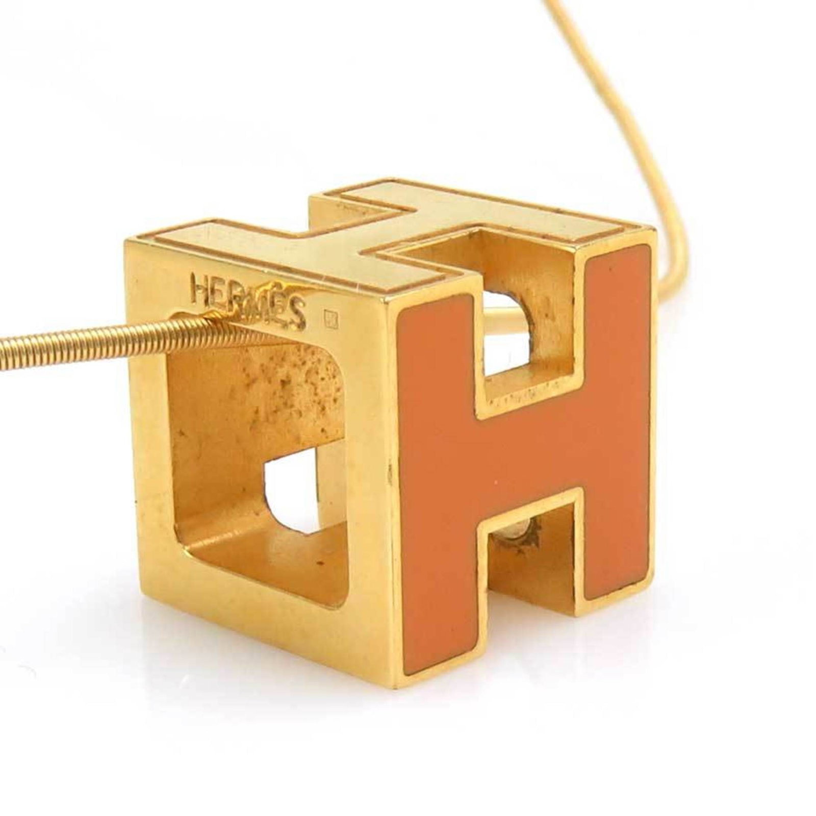 HERMES Metal Gold Orange: HERMES Metal Gold Orange The HERMES Metal Gold Orange necklace boasts a striking gold and orange hue, with a 42.5 cm chain and 11mm x 11mm pendant. This French-made piece features a metal construction