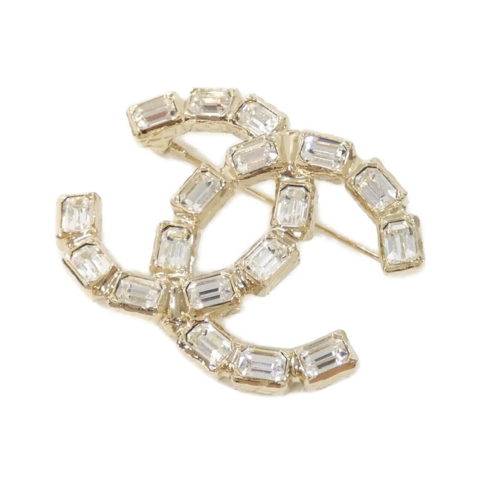 CHANEL Brooch Gold: CHANEL Brooch Gold The CHANEL Brooch Gold boasts a stunning gold finish and crystal stone, adding a touch of elegance to any outfit. Measuring 3.8cm x 5cm, this gently used brooch features minor