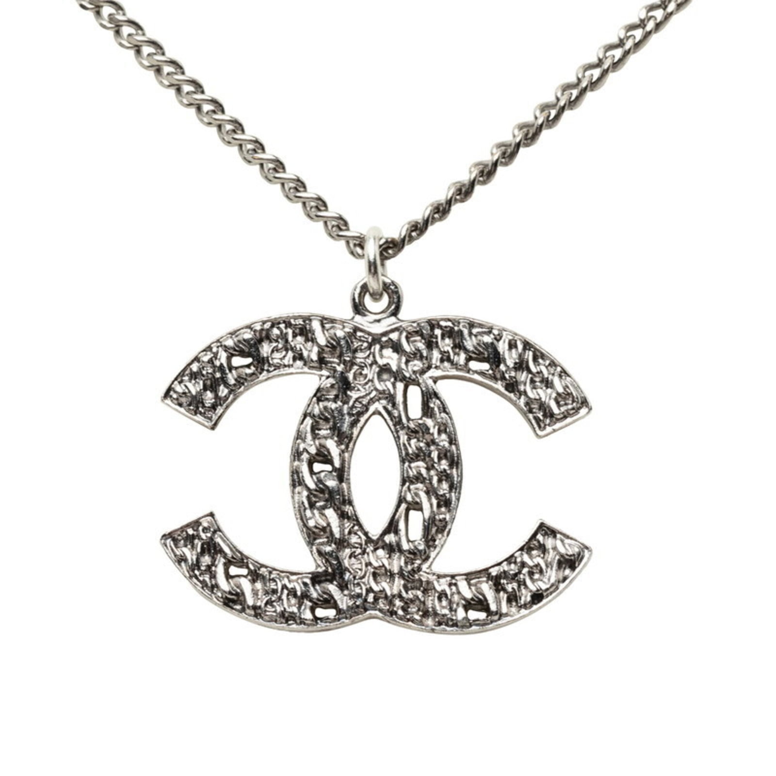 CHANEL Metal Silver: CHANEL Metal Silver Silver metal pendant from Chanel, featuring a 24mm x 28.3mm design with scratches and scuffs present. This good used pendant is made from metal and has a silver color, with a neck 