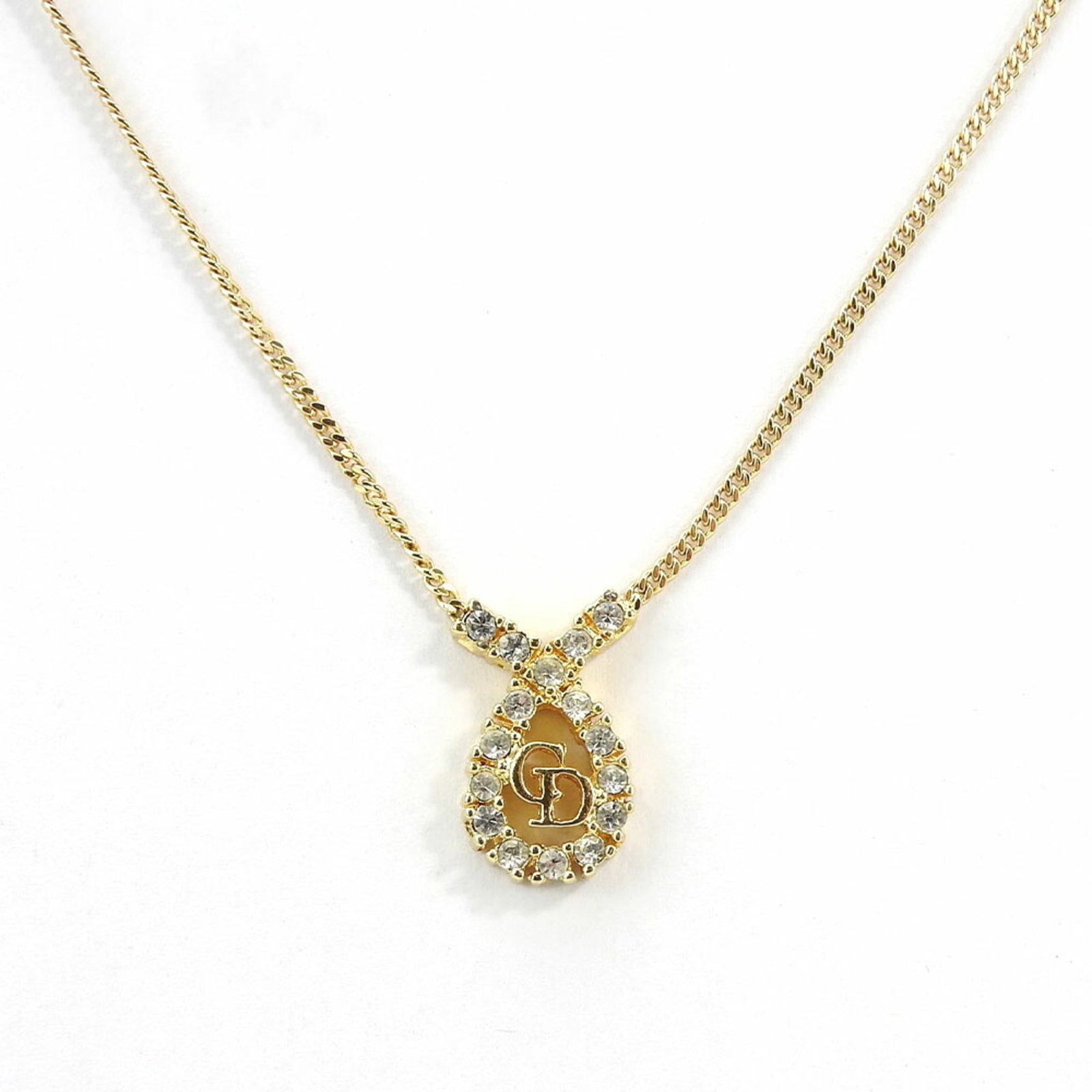 CHRISTIAN DIOR Metal: CHRISTIAN DIOR Metal Gently used Christian Dior gold metal necklace with a 17mm x 12mm rhinestone pendant, available in sizes 39.5 cm - 44.5 cm to fit various neck circumferences. This necklace