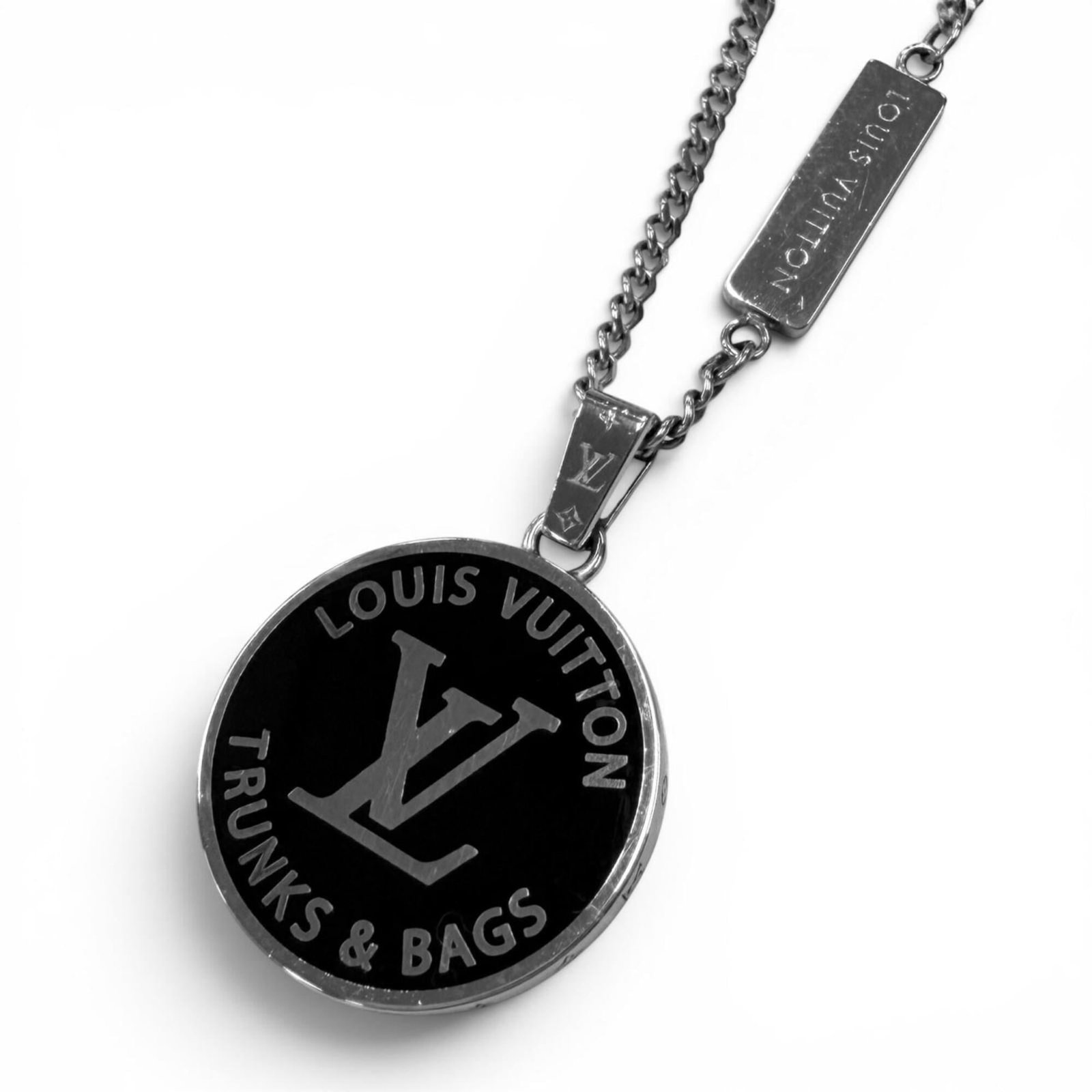 LOUIS VUITTON Black Silver: LOUIS VUITTON Black Silver The Louis Vuitton Black Silver Necklace is a sleek and sophisticated accessory, featuring a 22mm silver pendant with a black background. This gently used necklace has a