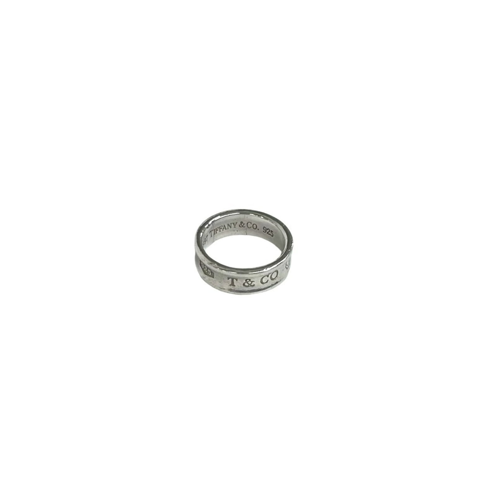 TIFFANY Band Ring Silver 925: TIFFANY Band Ring Silver 925 Silver 925 Tiffany band ring, a classic design with a subtle sheen, is available in a US size 6.5. The ring features a silver band with visible wear and scratches, giving 