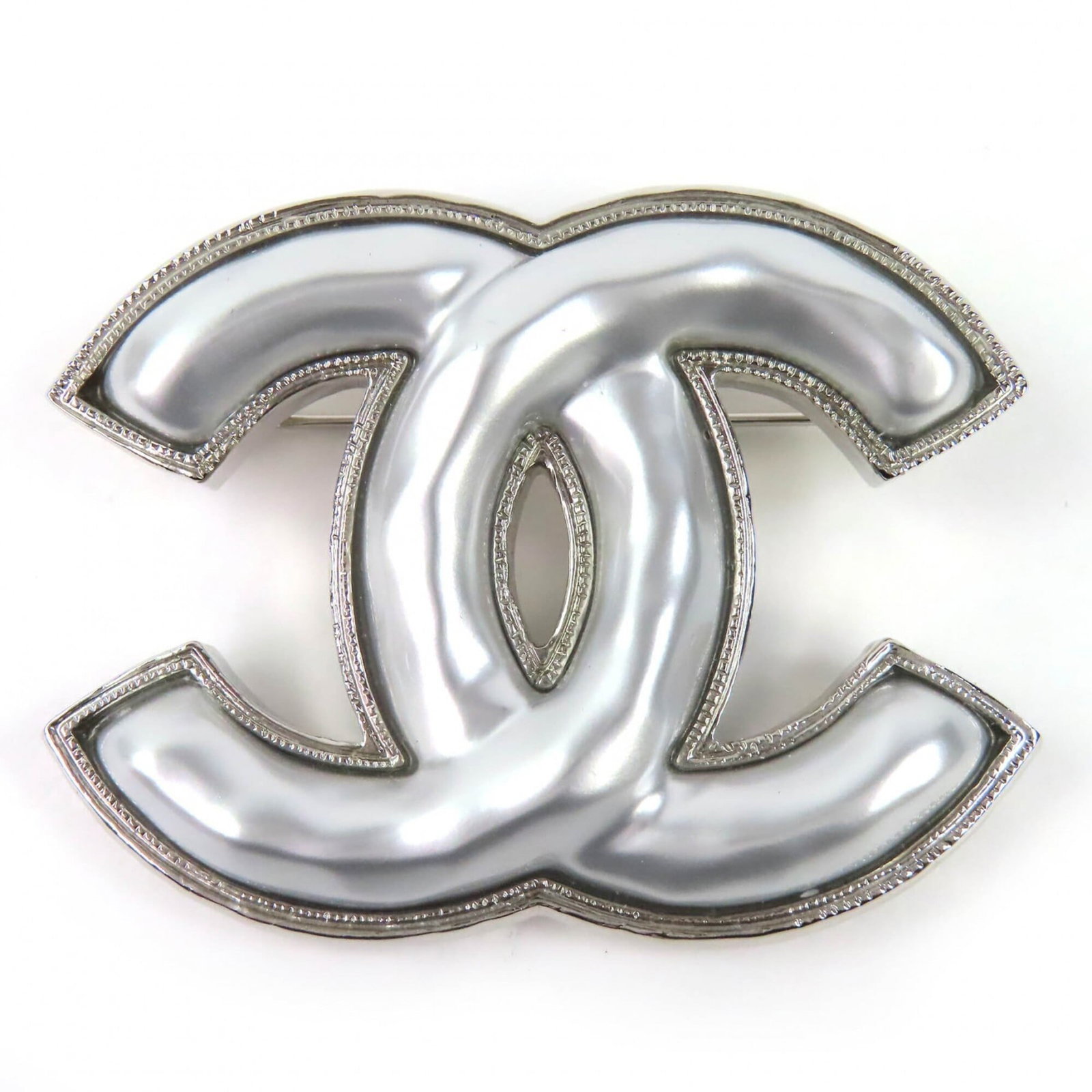 CHANEL Brooch Silver: CHANEL Brooch Silver The CHANEL Brooch Silver is a stunning piece of jewelry, bearing the iconic Chanel brand and crafted in Italy. Measuring 4.3cm x 5.8cm, it features a sleek silver design that look