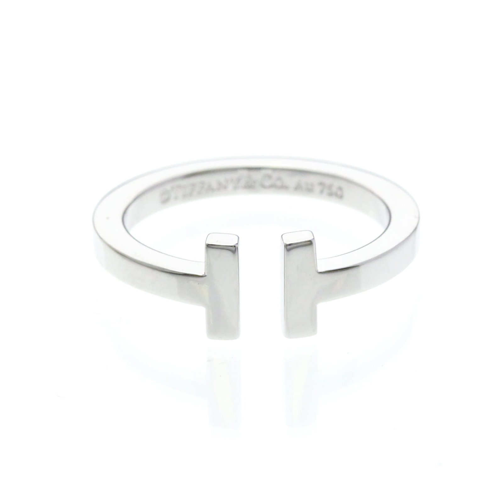 TIFFANY Band Ring White Gold (18K): TIFFANY Band Ring White Gold (18K) Tiffany's iconic T Square band ring is a timeless fashion statement in white gold (18K). This gently used band ring features a sleek design with minor signs of wear,