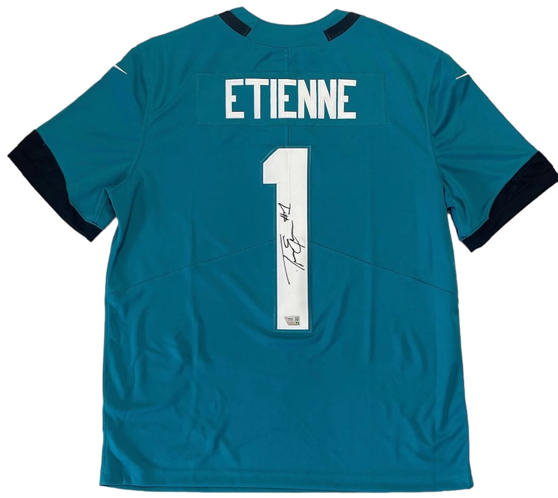 Travis Etienne AutographedAuthentic Jacksonville Jaguars Jersey (Fanatics): Travis Etienne AutographedAuthentic Jacksonville Jaguars Jersey (Fanatics) Travis Etienne's jersey number is signed in black sharpie across the back. This authentic jersey bears the signature of the p