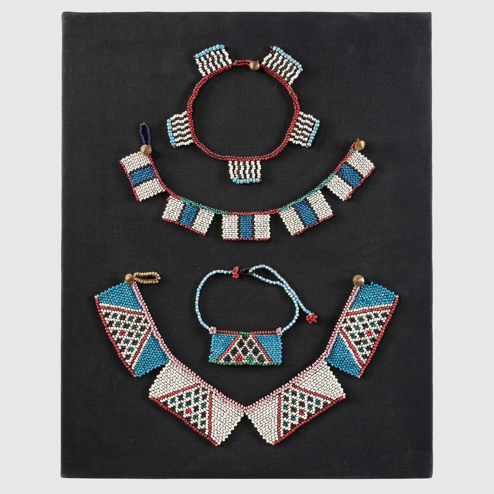 SELECTION OF ZULU BEADWORK SOUTHERN AFRICA: beads, metal and fibre string, a selection of Zulu beadwork presented on a bespoke wood and fabric backing (Dimensions: frame 51.5 x 40cm)(frame 51.5 x 40cm)Footnote: Provenance: Private collection, U