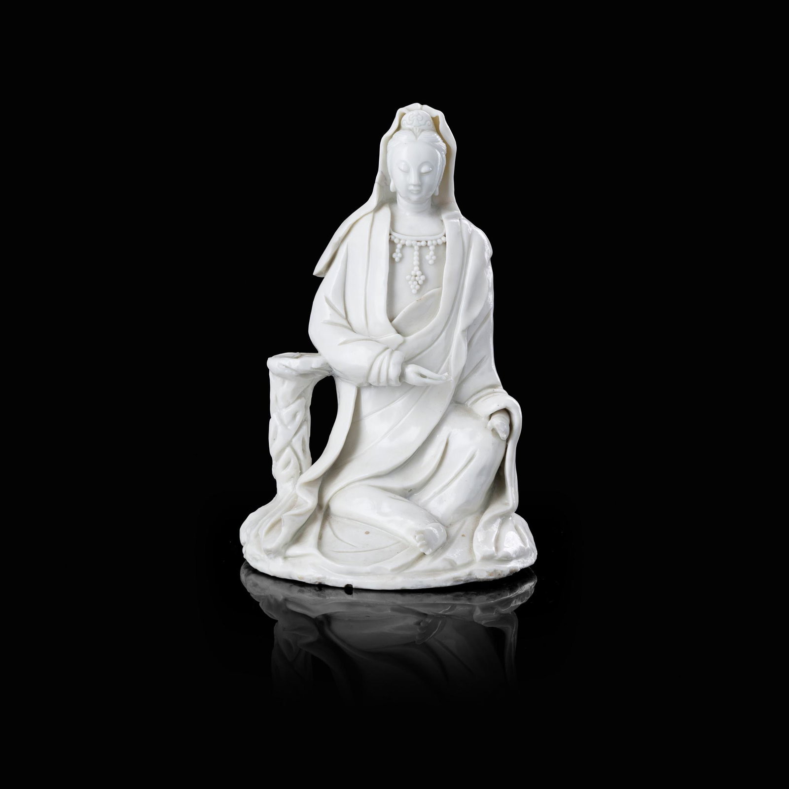 DEHUA FIGURE OF GUANYIN: seated in royal ease pose, right elbow resting on an elevated podium, with serene expression (20cm high) Footnote: Provenance: Collection of Dr John A Packer, Edinburgh