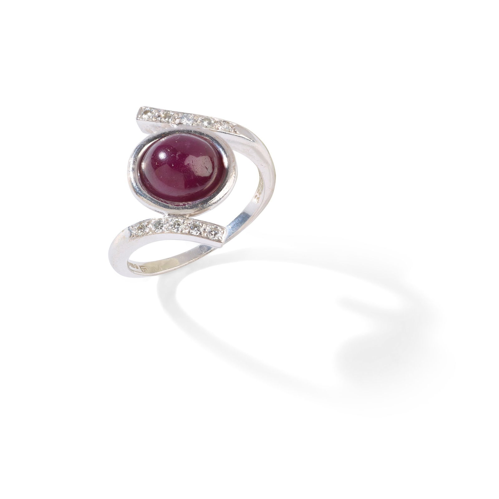 § Andrew Grima: A ruby and diamond ring, 1979: § Andrew Grima: A ruby and diamond ring, 1979 Collet-set with a cabochon ruby, between crossover design brilliant-cut diamond shoulders, signed Grima, rubbed maker's mark, UK hallmark (Ring size: