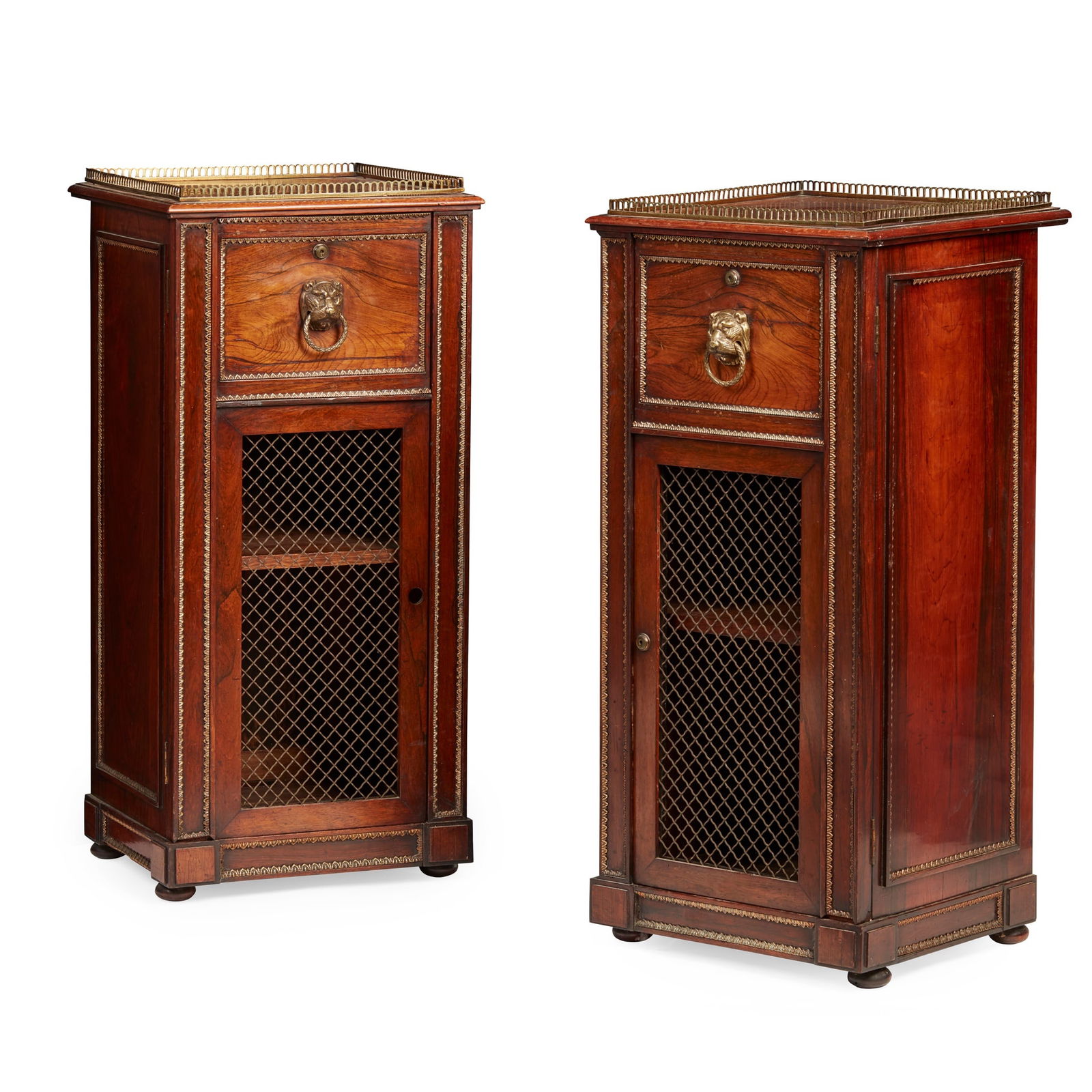 Y PAIR OF REGENCY ROSEWOOD AND BRASS PEDESTAL CABINETS, IN THE MANNER OF JOHN MCLEAN EARLY 19TH: Y PAIR OF REGENCY ROSEWOOD AND BRASS PEDESTAL CABINETS, IN THE MANNER OF JOHN MCLEAN EARLY 19TH CENTURY the square tops with pierced brass galleries above cupboard doors with brass lion mask handles a