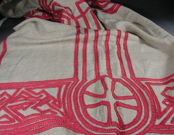 An Arts and Crafts table runner,of recta: An Arts and Crafts table runner,of rectangular outline, the unbleached linen ground reserved with a dramatic Celtic inspired knotwotk pattern in red with bold stitching98cm x 108cm