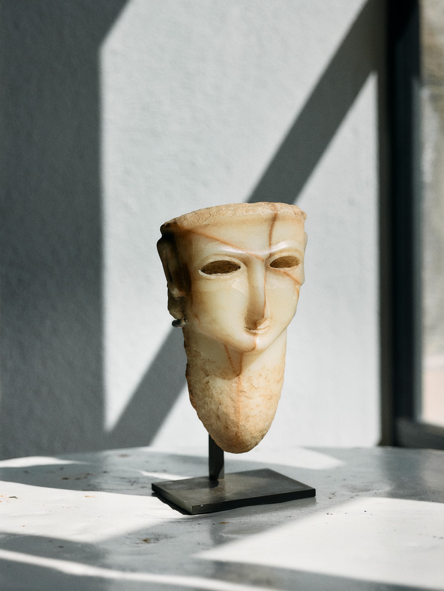 ANCIENT ARABIAN ALABASTER HEAD: ANCIENT ARABIAN ALABASTER HEAD SOUTHERN ARABIA, C. 1ST CENTURY B.C. carved banded alabaster, with long tapering neck, slender mouth, thin ridged nose, deeply recessed almond eyes for inlay, raised on 