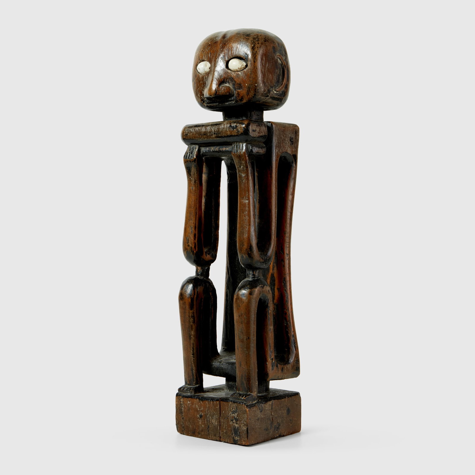 MOLUCCAS ISLANDS ANCESTOR FIGURE: MOLUCCAS ISLANDS ANCESTOR FIGURE LETTI ARCHIPELAGO, INDONESIA carved wood and cowrie shell, rising from a squared base, of slender and abstracted form, the standing body defined by elongated limbs and