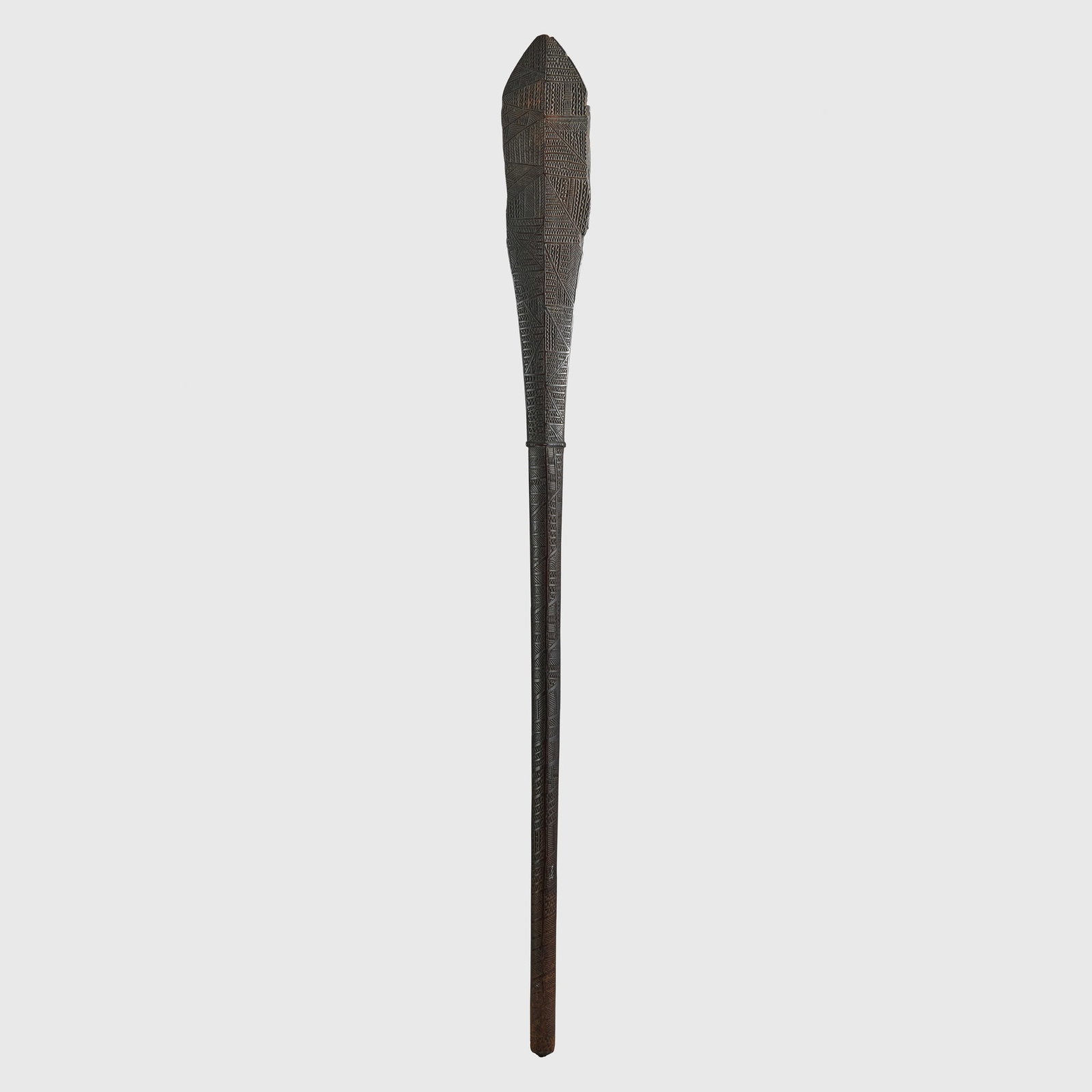 AKAU TAU CLUB: AKAU TAU CLUB TONGA ISLANDS carved wood, the long cylindrical shaft tapering toward the grip, a raised collar below a broad leaf-shaped head terminating in a pointed tip, the entire surface densely co