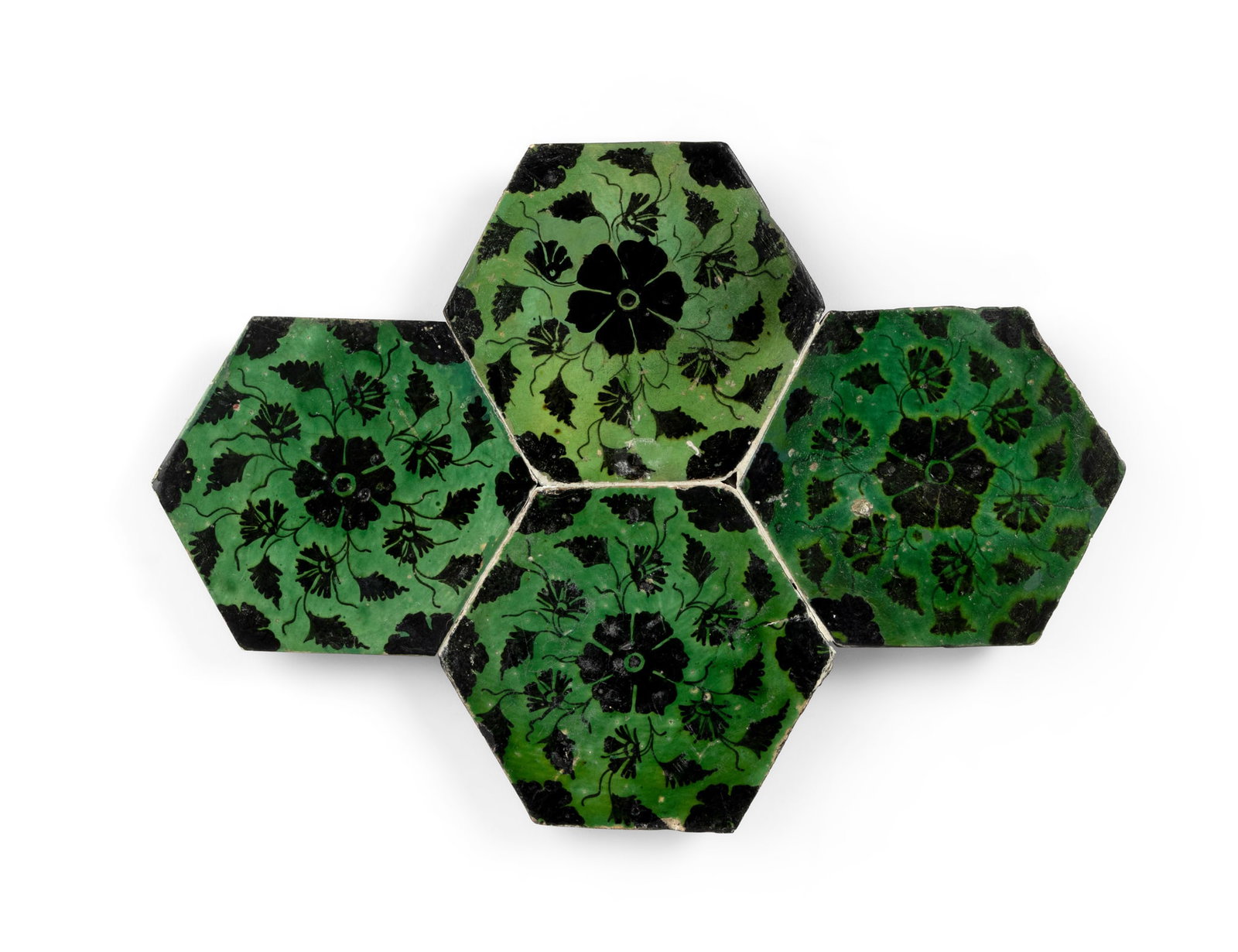 A GROUP OF FOUR 'DOME OF THE ROCK' POTTERY TILES: A GROUP OF FOUR 'DOME OF THE ROCK' POTTERY TILES OTTOMAN PROVINCES, JERUSALEM, 16TH CENTURY hexagonal, decorated in black under a green glaze with a central rosette surrounded by a whorl of carnations