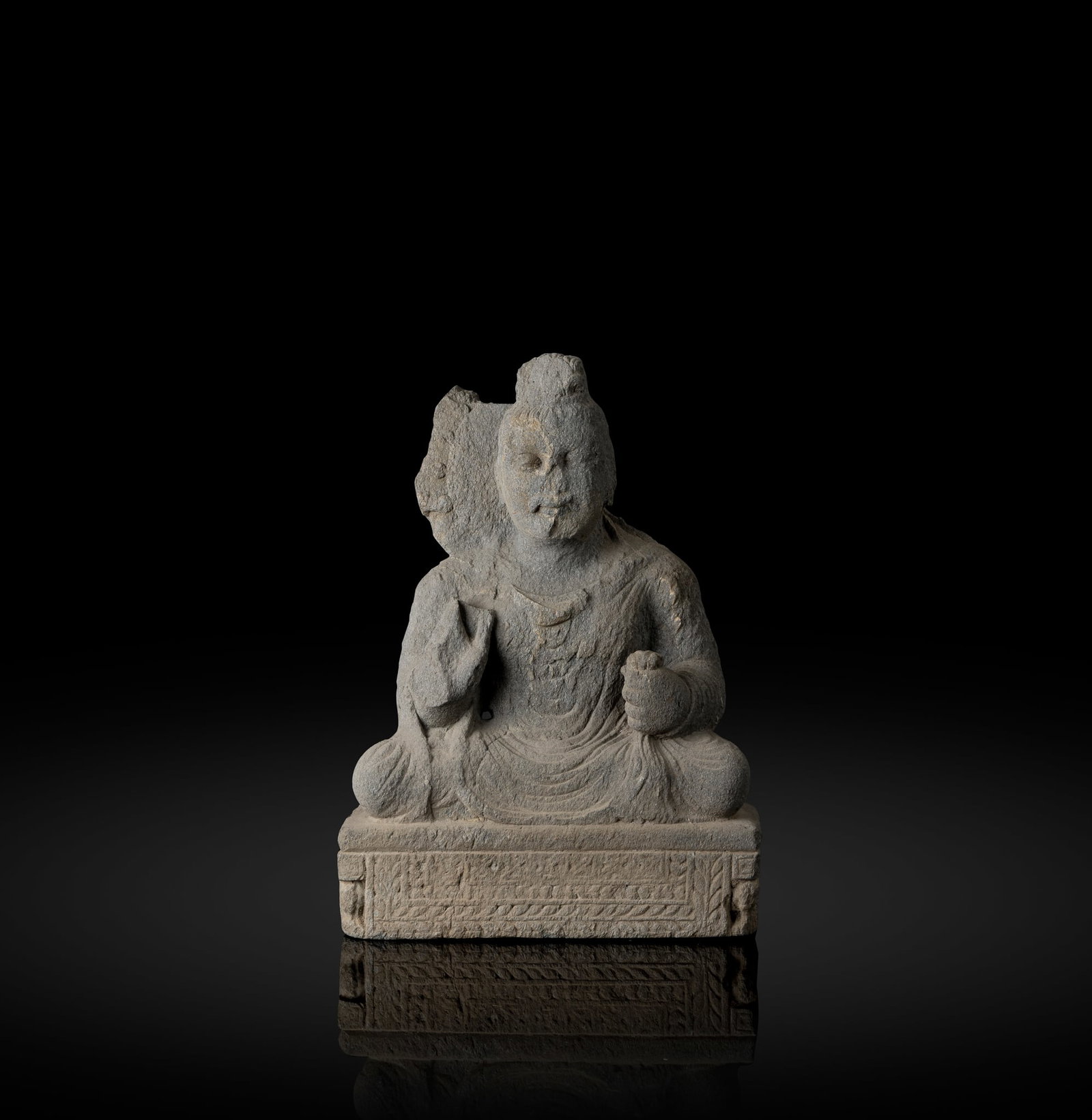 A GRAY SCHIST SEATED BUDDHA: A GRAY SCHIST SEATED BUDDHA NORTHWESTERN INDIA, GANDHARA, 2ND/ 3RD CENTURY carved, seated in dhyanasana with cascading folds of fabric clasped in one hand, pair of heavy lidded eyes, hair in wavy lock