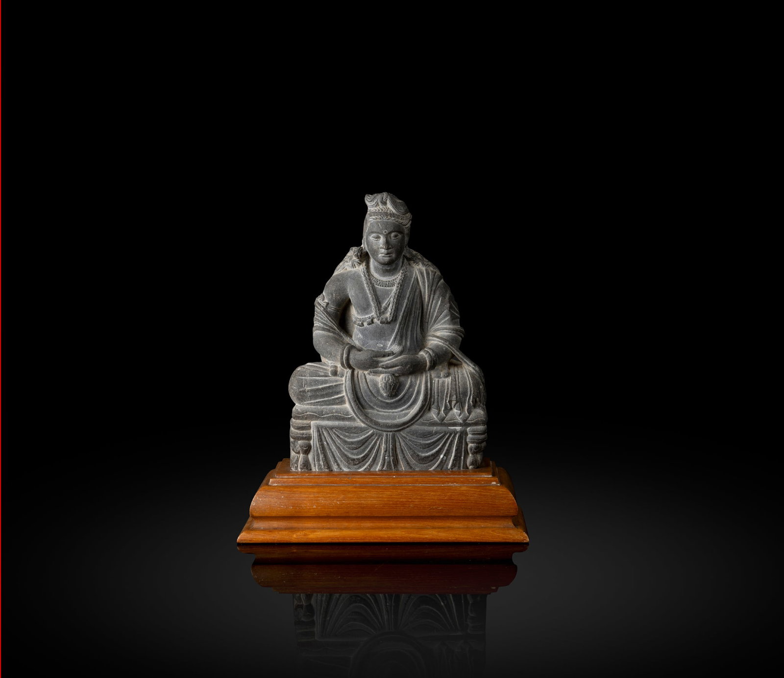 A GRAY SCHIST SEATED BUDDHA: A GRAY SCHIST SEATED BUDDHA NORTHWESTERN INDIA, GANDHARA, 3RD/ 4TH CENTURY finely carved seated in dhyanasana, possibly a Bodhisattva or Bodhisattva Maitreya, with hands in dhyanamudra in the lap, cas