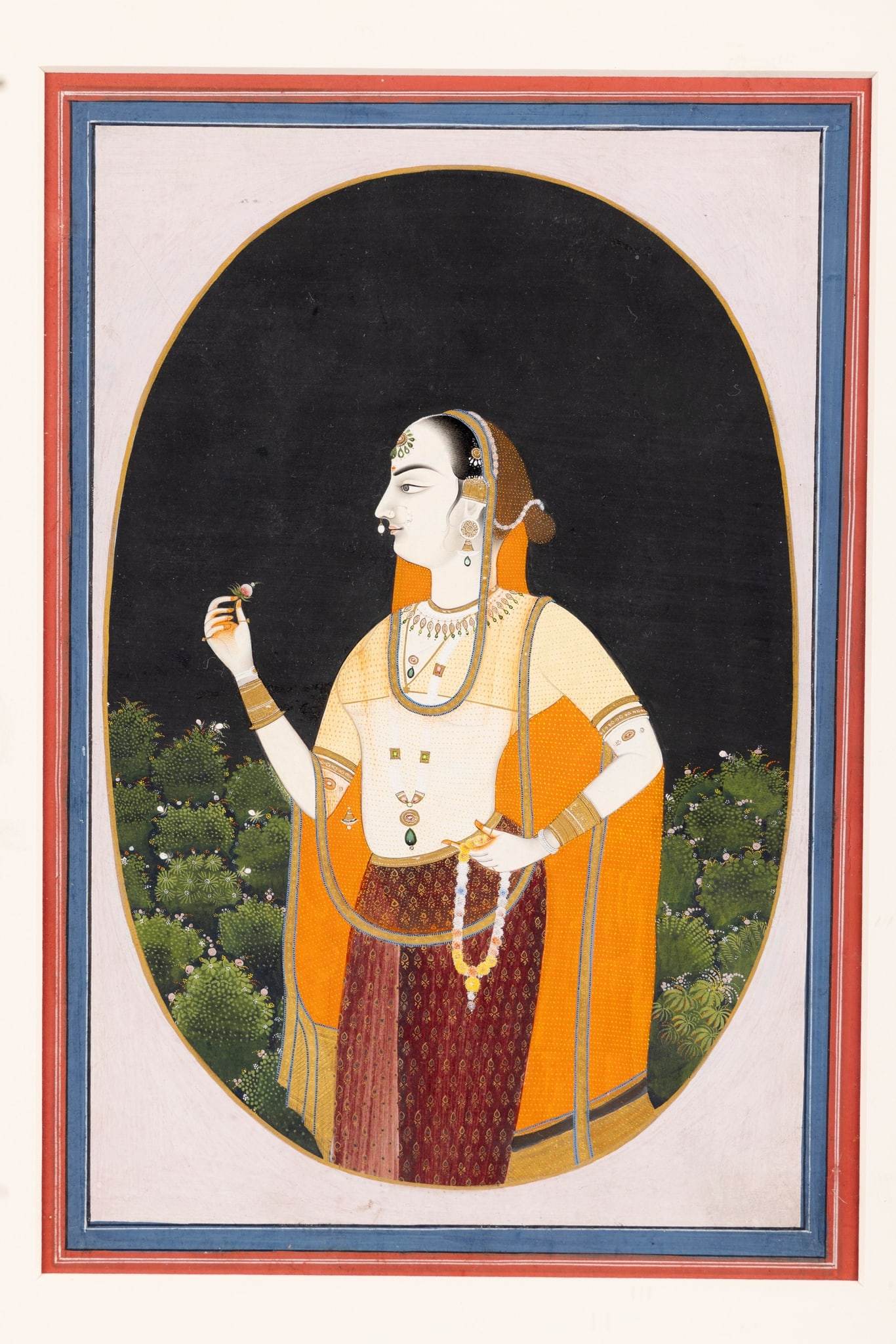 A BEJEWELLED MAIDEN OR COURTESAN: A BEJEWELLED MAIDEN OR COURTESAN INDIA, JAIPUR, CIRCA 1810-1820 gouache on paper heightened in gold, red and blue border with white margin lines, set within gardens at night time, depicting a bejewell