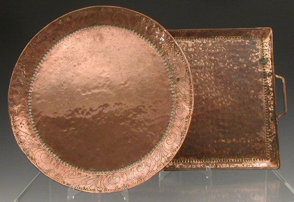 A John Pearson circular copper charger, . the rim: A John Pearson circular copper charger,. the rim chased with scrolling foliage, stamped monogram, 40cm diameter, and a John Pearson copper twin handled tray, with beaten finish, stamped monogram, 49.5