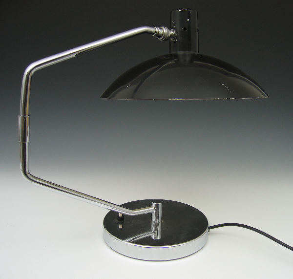 A Modernist chromium plated and enamelled lamp: A Modernist chromium plated and enamelled desk lamp designed by Clay Michie for Knoll International, the adjustable black shade supported by an angular arm on weighted circular base 42cm high