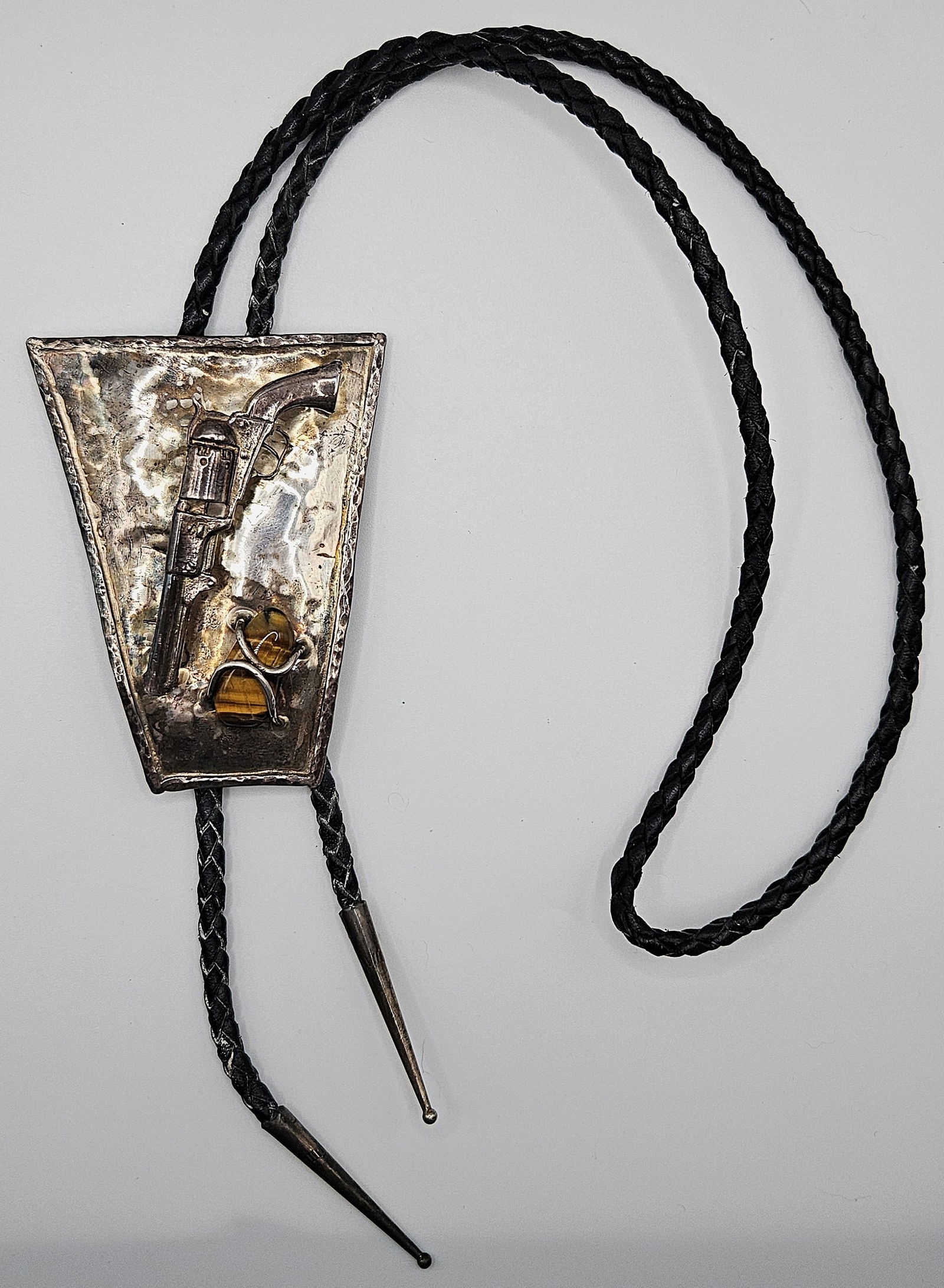 VINTAGE FANCY 6 SHOOTER WITH TIGER EYE STONESTERLING SILVER BOLO TIE: VINTAGE FANCY 6 SHOOTER WITH TIGER EYE STONESTERLING SILVER BOLO TIE. VERY RARE AND LARGE. Comes with leather cord . Size: bolo 3 3/8 x 2 5/8 in., total length 18 1/4 in. All measurements are approxim