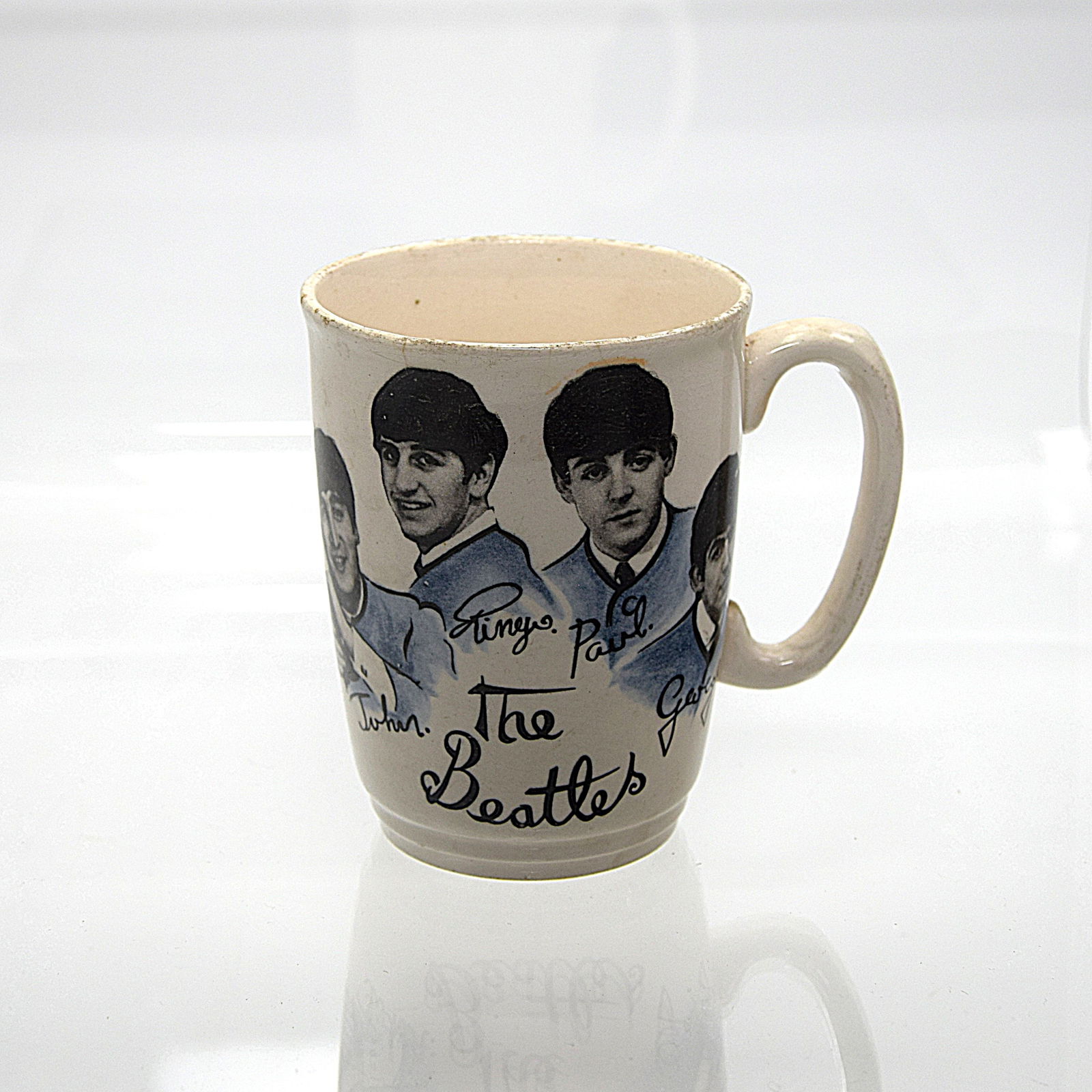THE BEATLES CERAMIC CUP: THE BEATLES CERAMIC CUP. Manufactured by Washington Pottery, England. Blue and Black Decal of BEATLES Fired on the side of the cup. Bottom of cup marked "ENGLAND". Size: 4in. high. All measurements ar