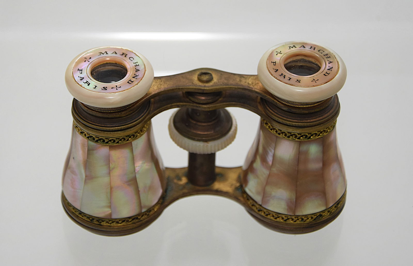ANTIQUE OPERA GLASSES BY MARCHAND PARIS, MOTHER OF PEARL: ANTIQUE OPERA GLASSES BY MARCHAND PARIS, MOTHER OF PEARL ACCENTS AND BRASS DETAILING. C. LATE 19- EARLY 20th CENTURY. Size: 4 in. wide by 2 1/2 in. high. Condition: Please see pictures. Provenance: NY