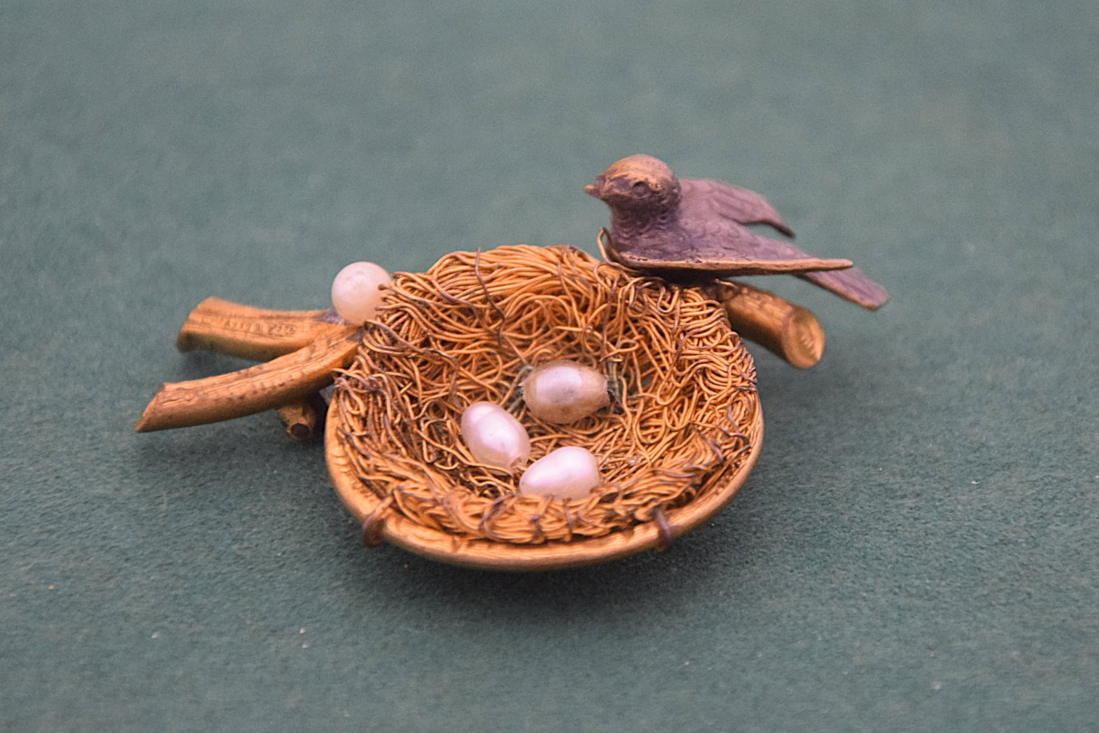 VINTAGE BIRD NEST BROOCH WITH PEARL EGGS GILT METAL NATURALISTIC DESIGN: CHARMING VINTAGE BROOCH FEATURING A NATURALISTIC BIRD PERCHED ATOP A FINELY WOVEN NEST, SET WITH FOUR IMITATION PEARL “EGGS.” CRAFTED IN GILT METAL WITH DELICATE WIREWORK FORMING THE NEST AND 
