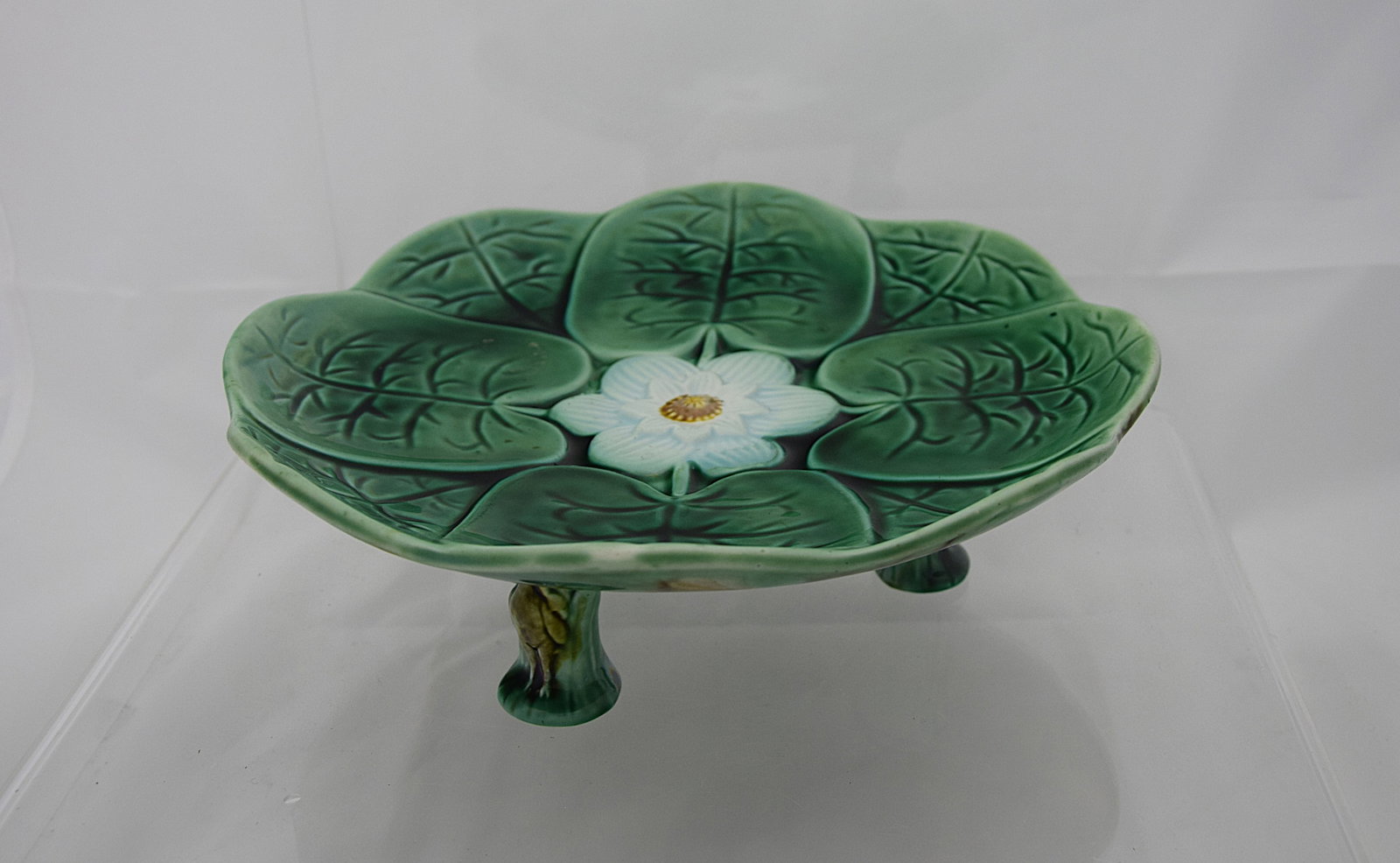 VIBRANT MAJOLICA LILY PAD FOOTED DISH NATURALISTIC FLORAL DESIGN EUROPEAN ART POTTERY: STRIKING NATURALISTIC MAJOLICA DISH MODELED AS A CLUSTER OF LILY PADS CENTERED BY A BLOOMING WHITE FLOWER, RENDERED IN RICHLY GLAZED GREEN TONES WITH DIMENSIONAL VEINING AND SCULPTURAL RELIEF. PROBABL