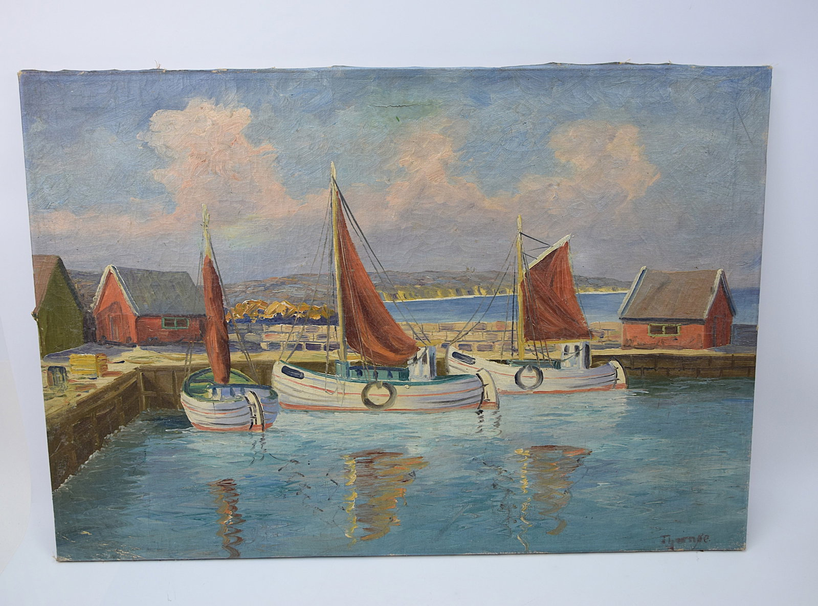 VINTAGE OIL PAINTING HARBOR SCENE WITH FISHING BOATS SIGNED “THOMÉ" (OR SIMILAR) 20TH CENTURY: CHARMING VINTAGE OIL ON CANVAS DEPICTING A QUIET HARBOR SCENE WITH THREE MOORED FISHING BOATS FEATURING DISTINCTIVE RED SAILS, SET AGAINST A COASTAL BACKDROP WITH DOCKSIDE BUILDINGS AND CALM REFLECTIV