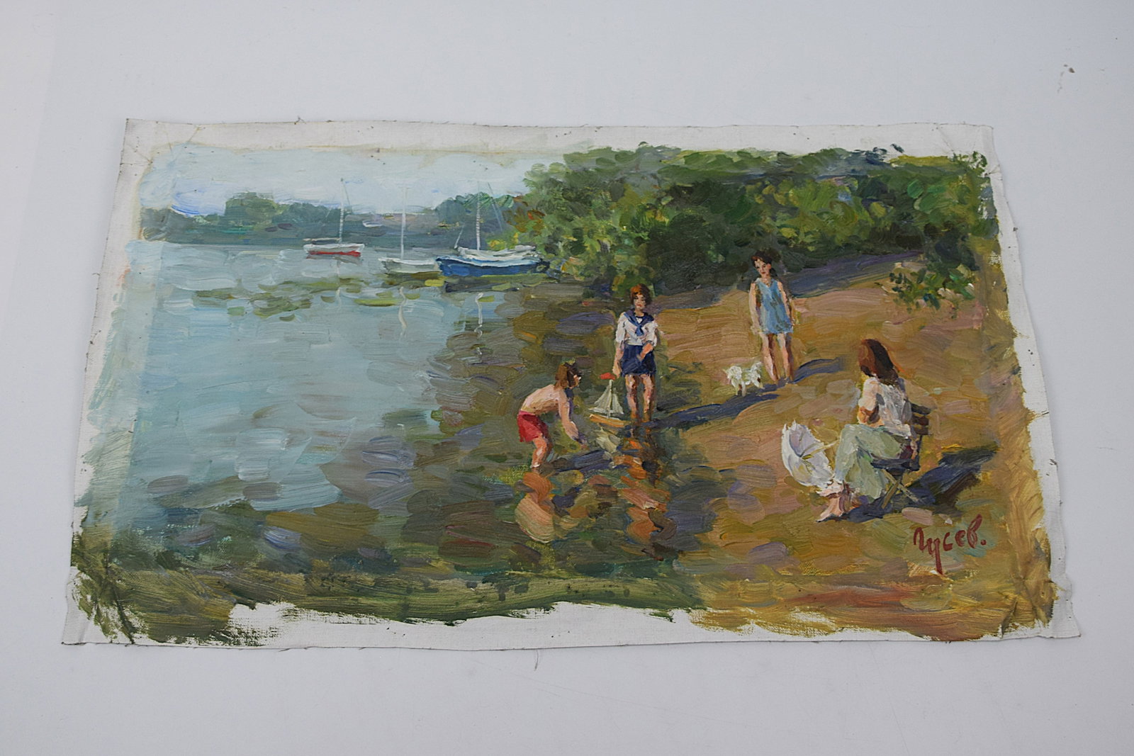 ORIGINAL OIL PAINTING FIGURAL RIVERBANK SCENE SIGNED (RUSSIAN SCHOOL): ORIGINAL MID-20TH CENTURY OIL ON CANVAS (UNSTRETCHED), DEPICTING A CHARMING OUTDOOR RIVERBANK SCENE WITH CHILDREN PLAYING NEAR THE WATER’S EDGE, ACCOMPANIED BY A SEATED ADULT FIGURE; SAILBOATS ARE V