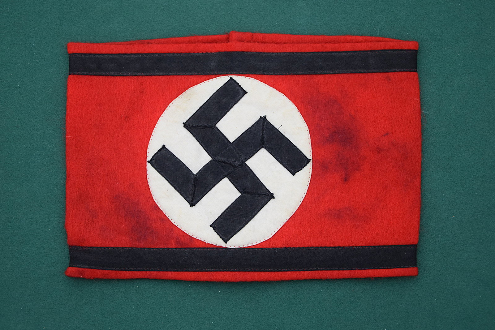 ORIGINAL WAFFEN SS ARMBAND RED WOOL SWASTIKA THIRD REICH ERA: ICONIC THIRD REICH PERIOD WAFFEN SS ARMBAND EXECUTED IN RED WOOL WITH BLACK TRIM AND CENTRAL WHITE ROUNDEL BEARING APPLIQUÉ BLACK SWASTIKA, CONSTRUCTED IN CLASSIC MULTI-PIECE FORM WITH MACHINE STITCH