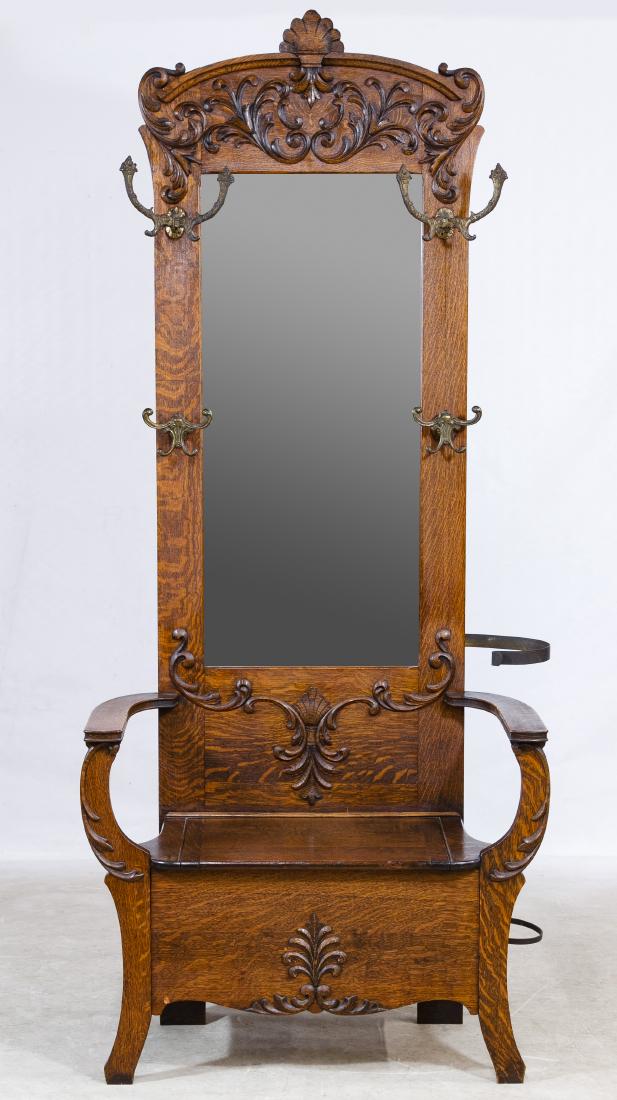Oak Hall Tree: Oak Hall Tree Having an armed seat with hinged compartment and a carved wood framed beveled mirror back with ornate coat and hat hooks and umbrella bracket Height: 82.00 inches, Width: 35.00 inches, D