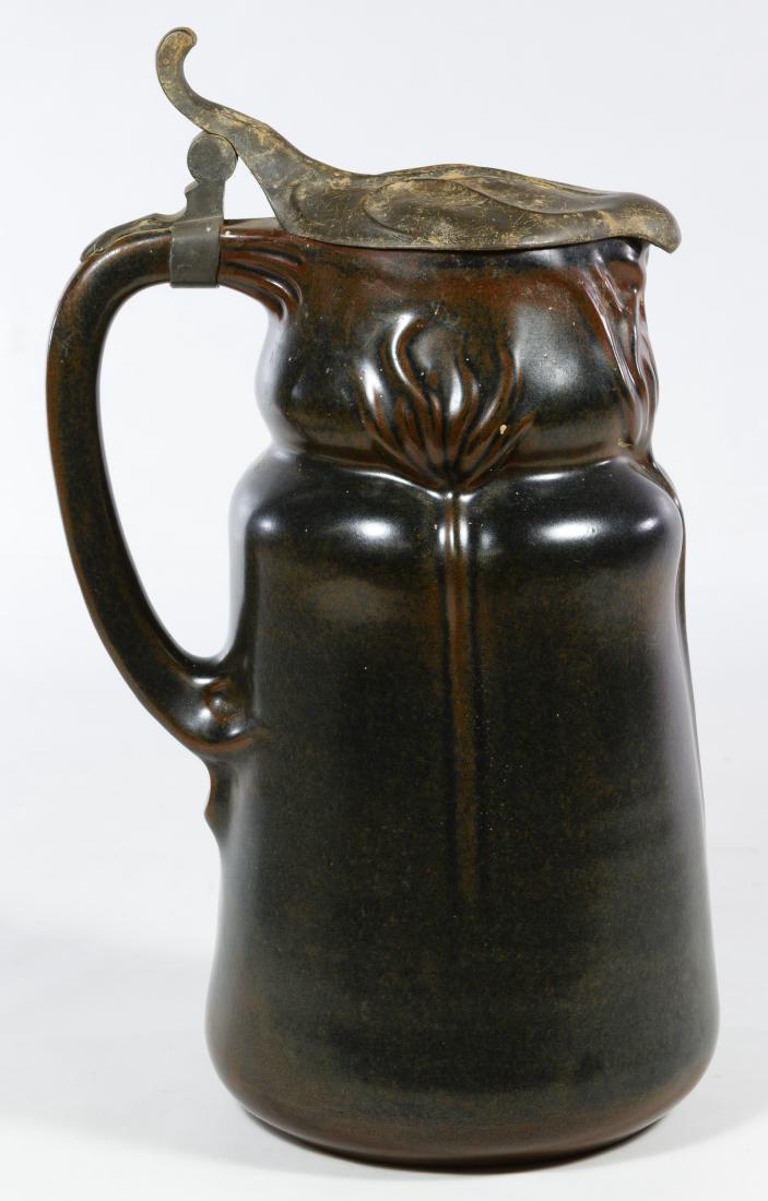 Art Nouveau German Stein by J J Scharvogel: Art Nouveau German Stein by J J Scharvogel Having a dark red glaze with stylized floral relief on the body, a pewter lily pad style lid and the maker mark on the underside Height: 13.50 inches Categor
