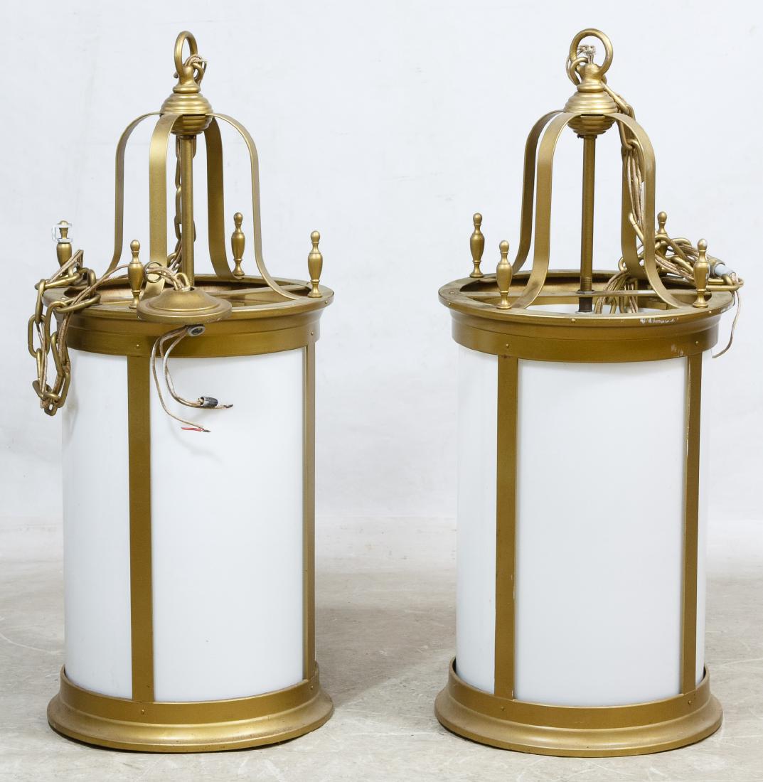 Architectural Lamps: Architectural Lamps Two ceiling fixtures having white glass cylinders inside a cast metal frame painted gold, each having three lights and an internal shade; together with ceiling caps Height: 38.00 i