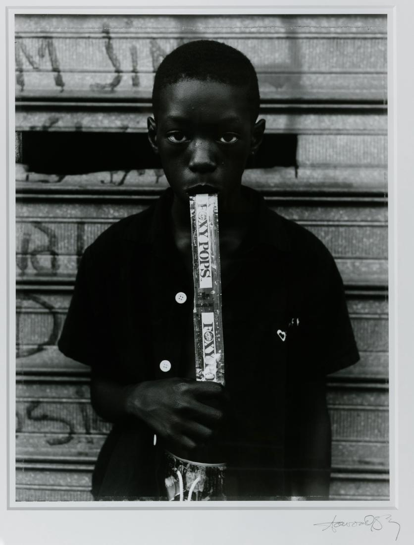 Dawoud Bey (American, b.1953) 'Boy Eating a Foxy Pop': Dawoud Bey (American, b.1953) 'Boy Eating a Foxy Pop' Silver Print Exhibition Photograph c.1995, signed lower right on matting; photograph #35 from the 'Dawoud Bey: Portraits 1975-1995' exhibit at the