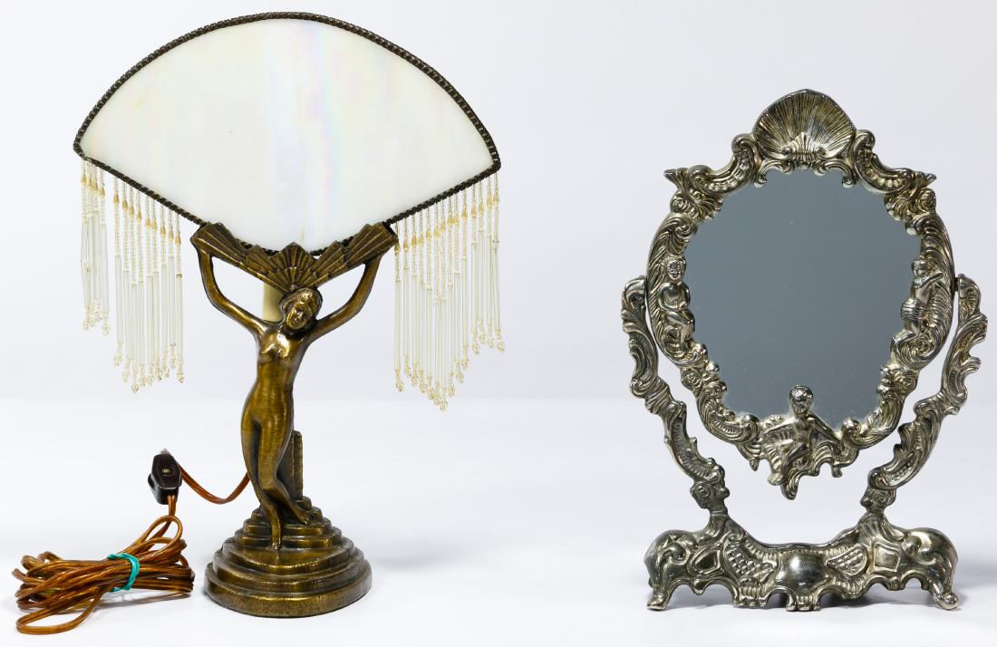Art Deco Lamp: Art Deco Lamp Metal lamp having an iridescent glass shade with attached beading; together with an Art Nouveau metal swivel mirror having a shell, flower, scroll, plume and infant motif Condition: Very