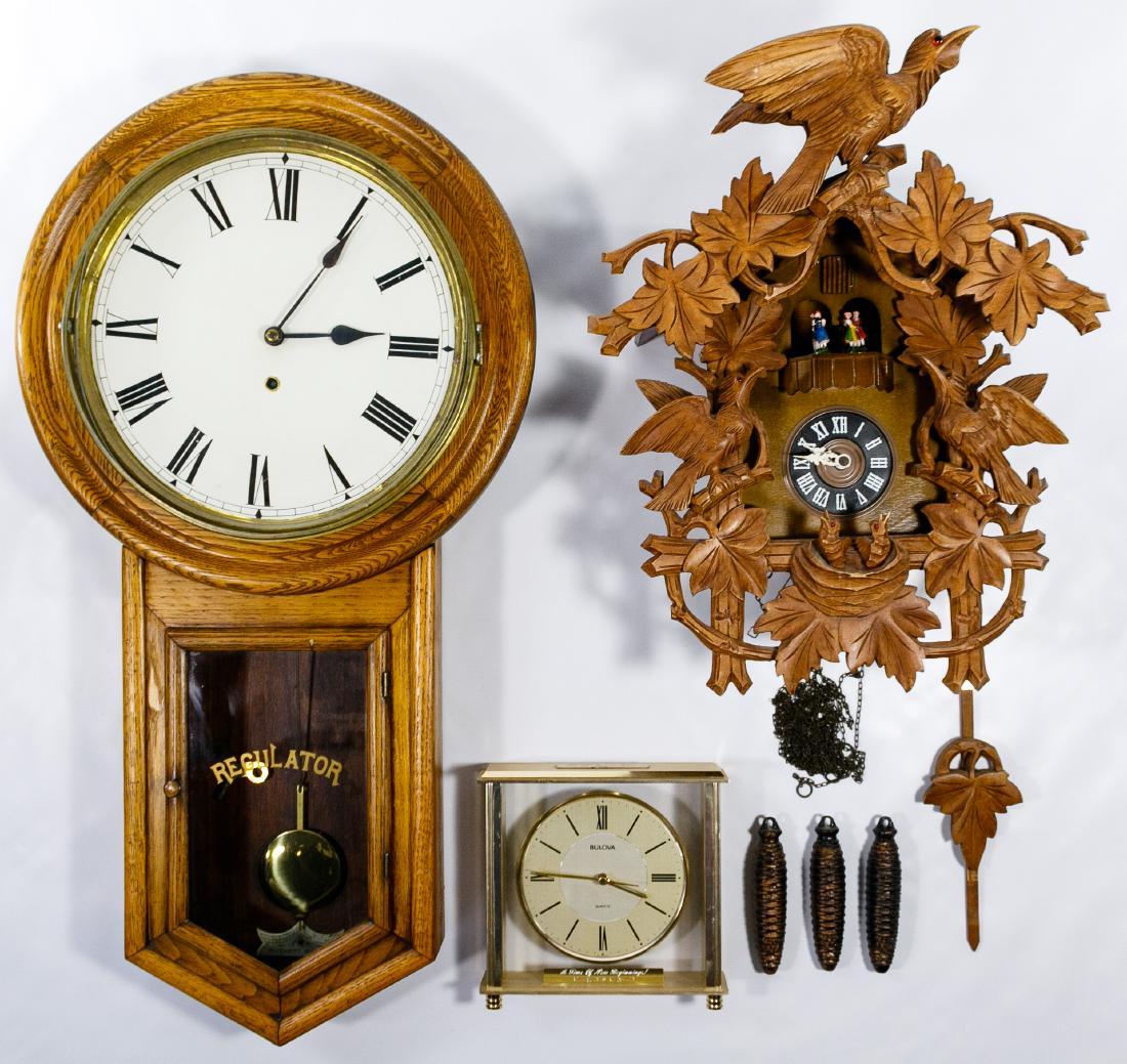 Regulator, Cuckoo and Desk Clock Assortment: Regulator, Cuckoo and Desk Clock Assortment Three clocks including an oak regulator by Waterbury Clock Co., a wood carving birdhouse cuckoo with rotating mini dancing figurines, and a Bulova quartz de