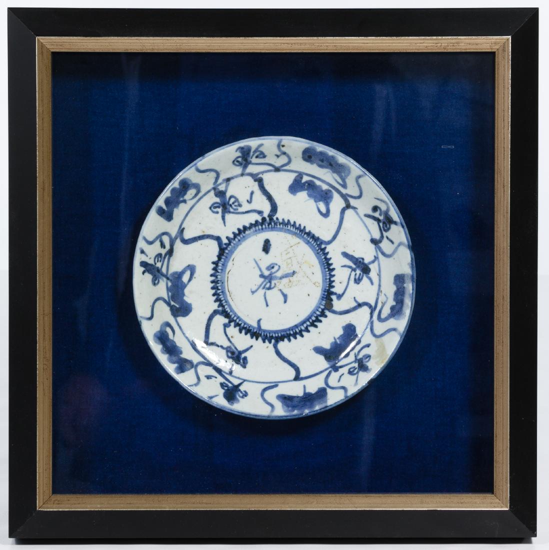 Chinese Blue and White Plate in Shadowbox: Chinese Blue and White Plate in Shadowbox Earthenware plate mounted on blue velvet, framed in black and gold, having cutout through dustcover to show markings on plate Condition: Very Good, no damage 