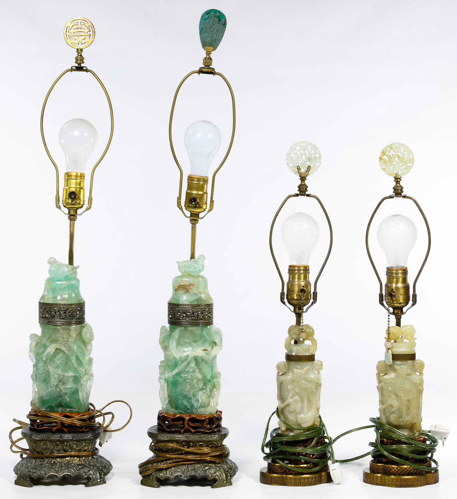 Asian Jadeite Jade Lamp Assortment: Asian Jadeite Jade Lamp Assortment Two pair of carved lamps depicting birds and plants, taller set having heavy cast metal bases, carved wood foot, articulated metal collars and separate jadeite bell-