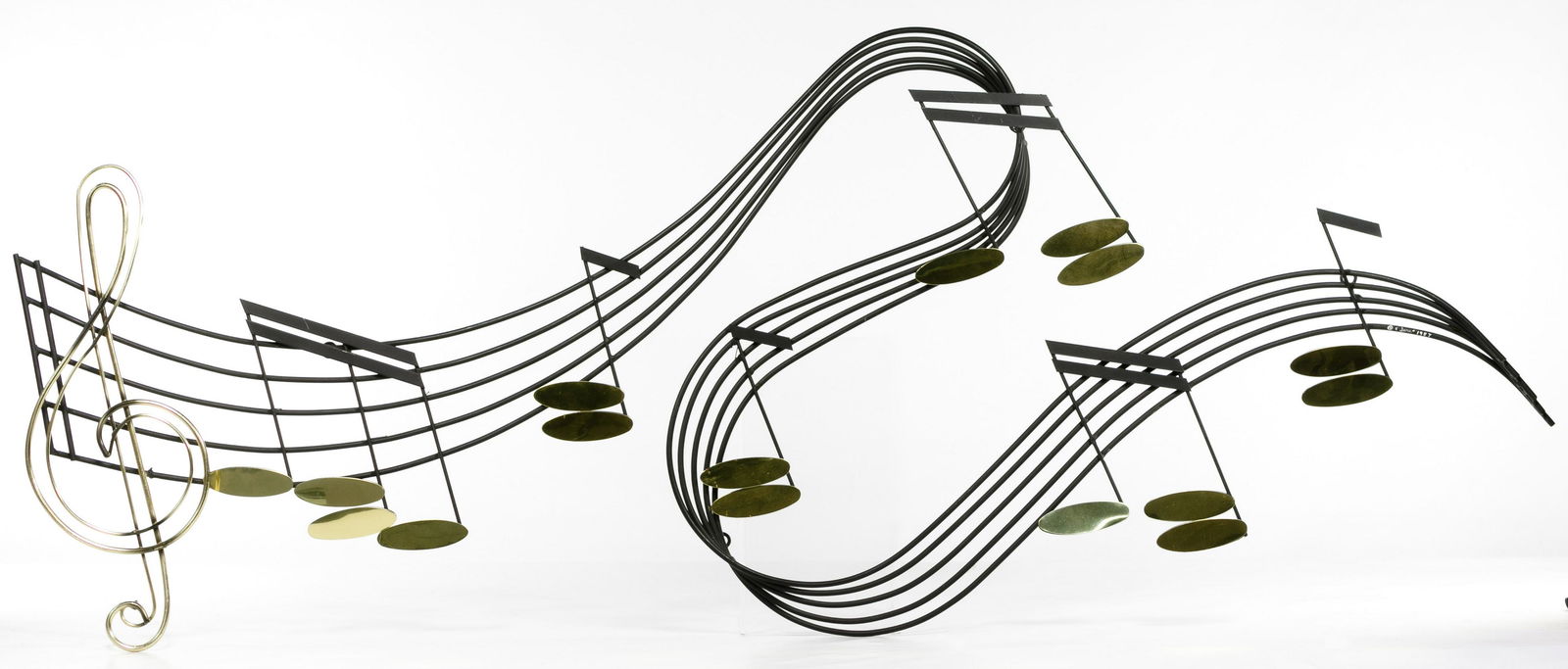 Curtis Jere (American, 1910-2008) Metal Sculpture: Curtis Jere (American, 1910-2008) Metal Sculpture 1987, signed lower right, wall hanging that depicts a dramatically curved bar of music, made of black and gold-tone metal Condition: Very Good, overal
