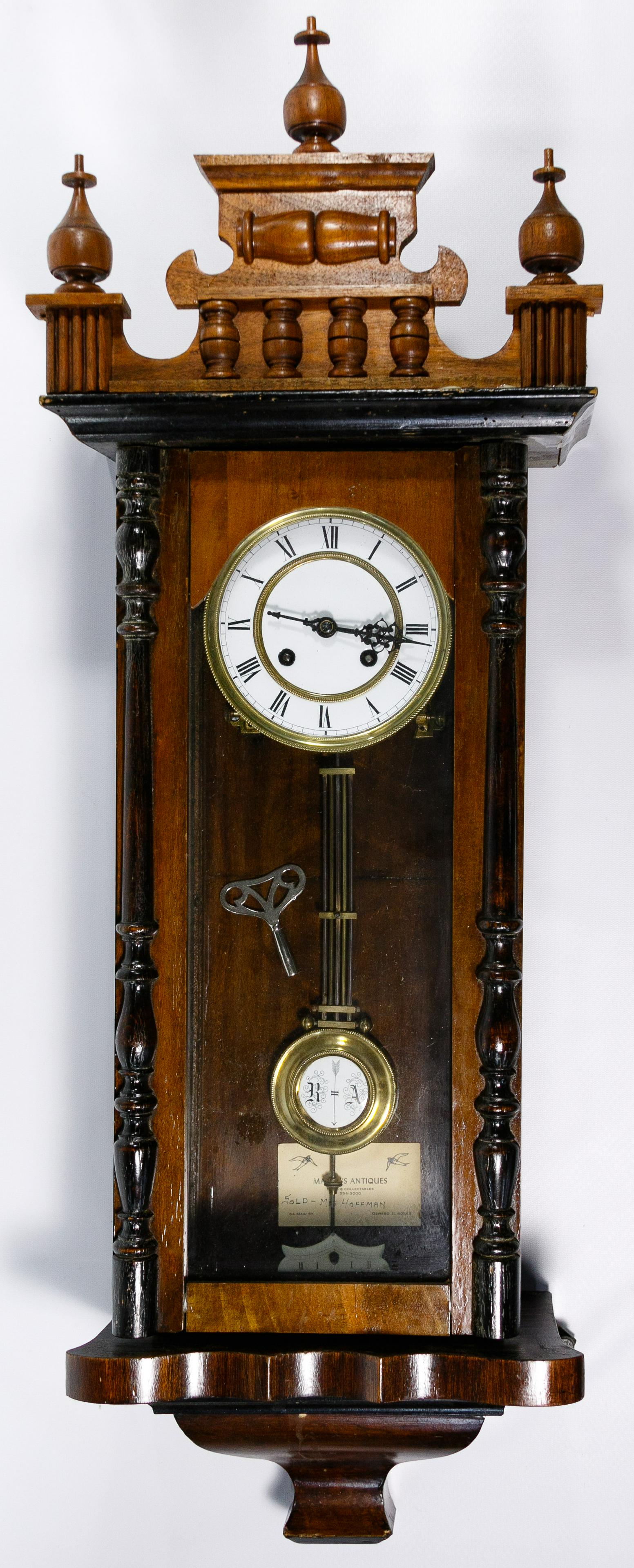 Walnut Cased Wall Clock: Walnut Cased Wall Clock Having a porcelain dial and columned case including pendulum and key Condition: Fair, moderate wear to the case overall; nicks, scratches and areas of finish loss overall; visi
