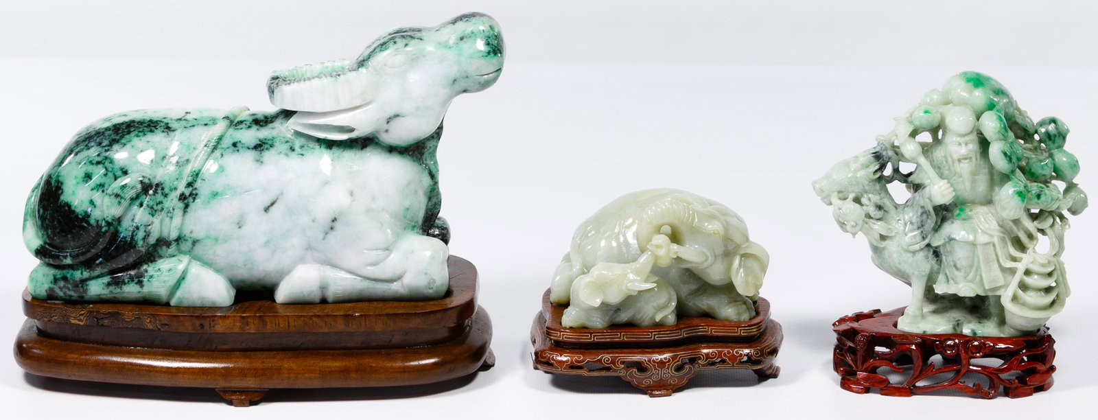 Asian Jadeite Jade Carved Statue Assortment: Asian Jadeite Jade Carved Statue Assortment Three items including a light green mother and baby elephant having interlocking trunks on carved rosewood stand, a large carved water buffalo on custom mad