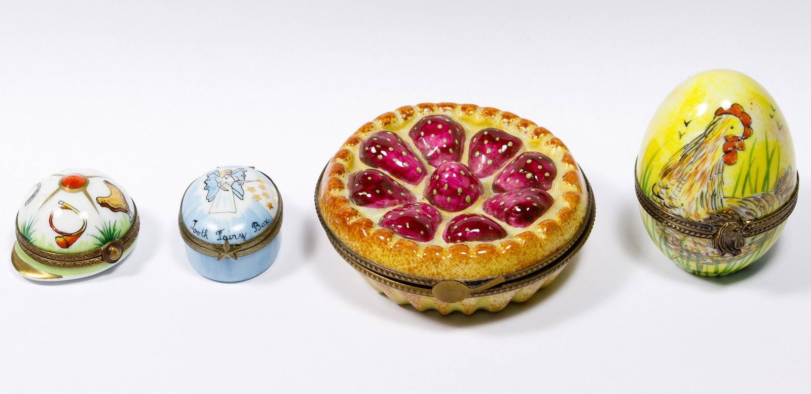Limoges Box Assortment: Limoges Box Assortment Four boxes including an egg depicting a chicken, a strawberry pie, an oval depicted as 'Tooth Fairy Box' and a riding hat having an equestrian motif; marked on underside Conditi